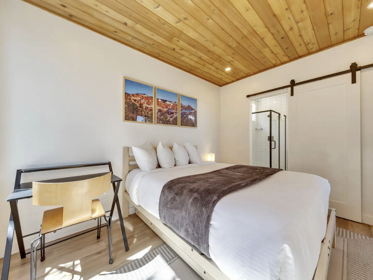 Bedroom featuring a plank wood ceiling, light wood-finish flooring, and white walls