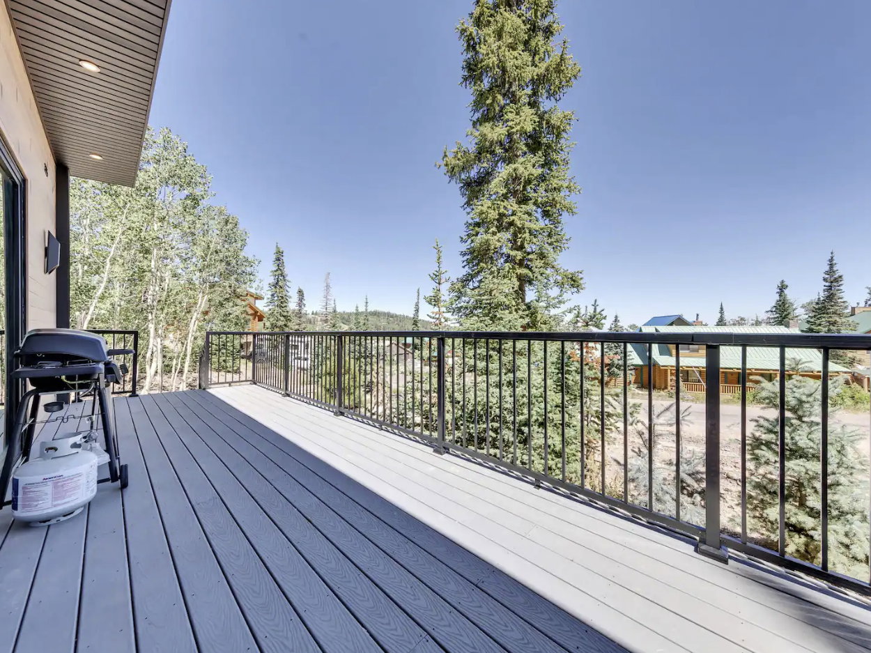 Spacious outdoor deck featuring composite decking, black metal railings, and an exterior wall with vertical wood siding