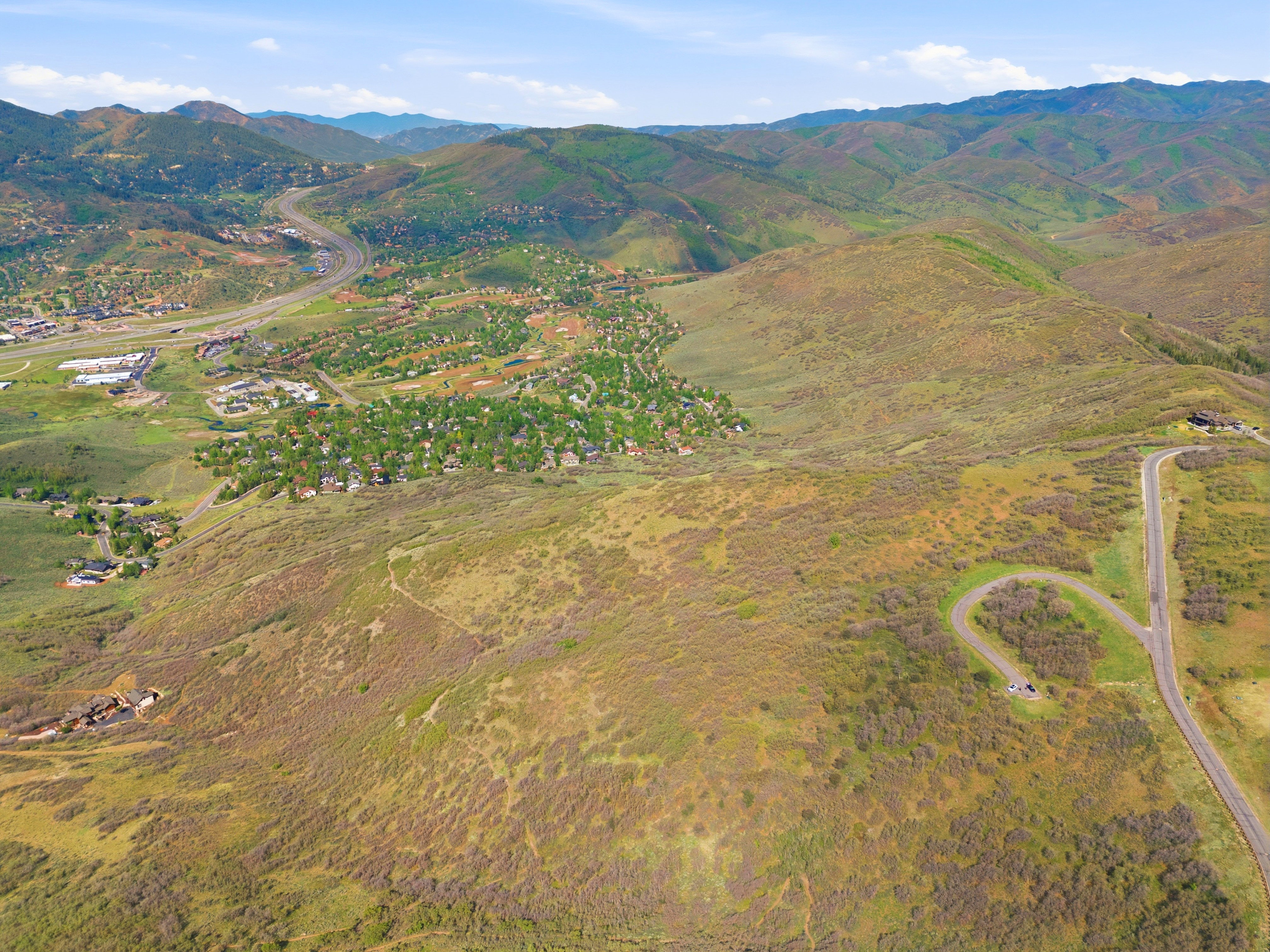Expansive mountainous terrain featuring scattered residential areas and winding roads
