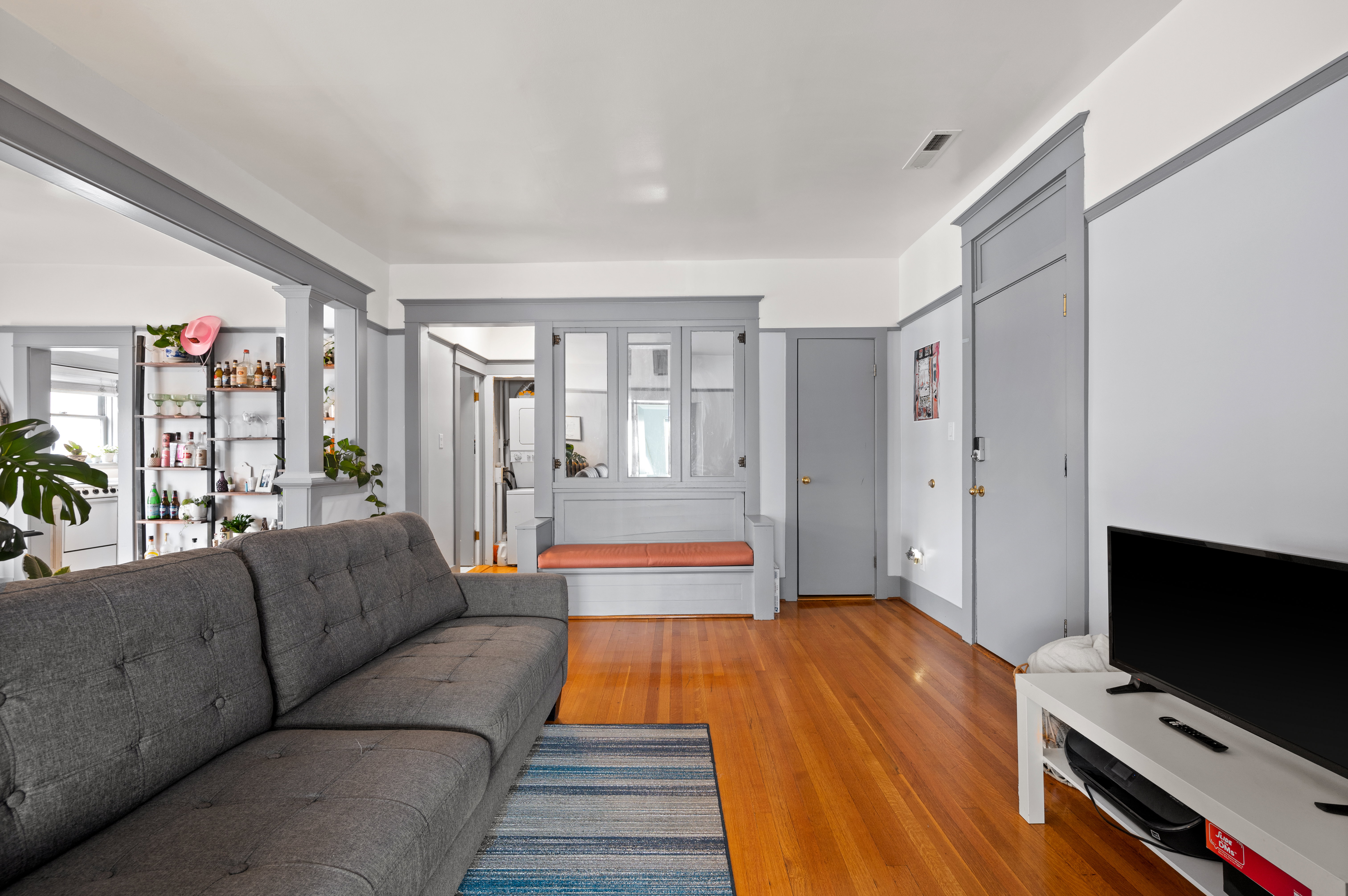 Expansive room featuring warm wood flooring, crisp white walls, and gray trim work