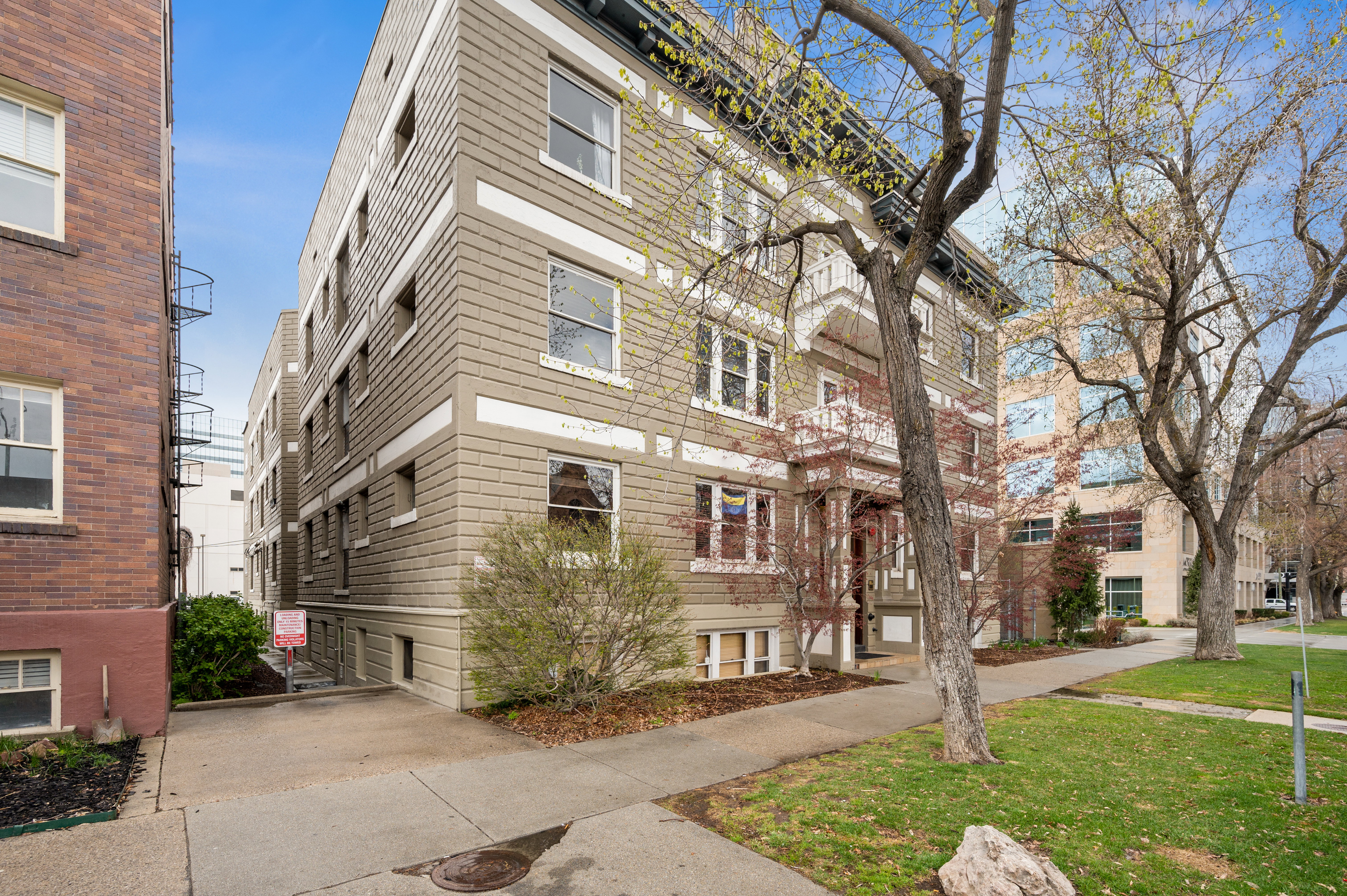 Multi-story building featuring textured siding with contrasting trim, multiple windows, and a decorative front entrance with columns