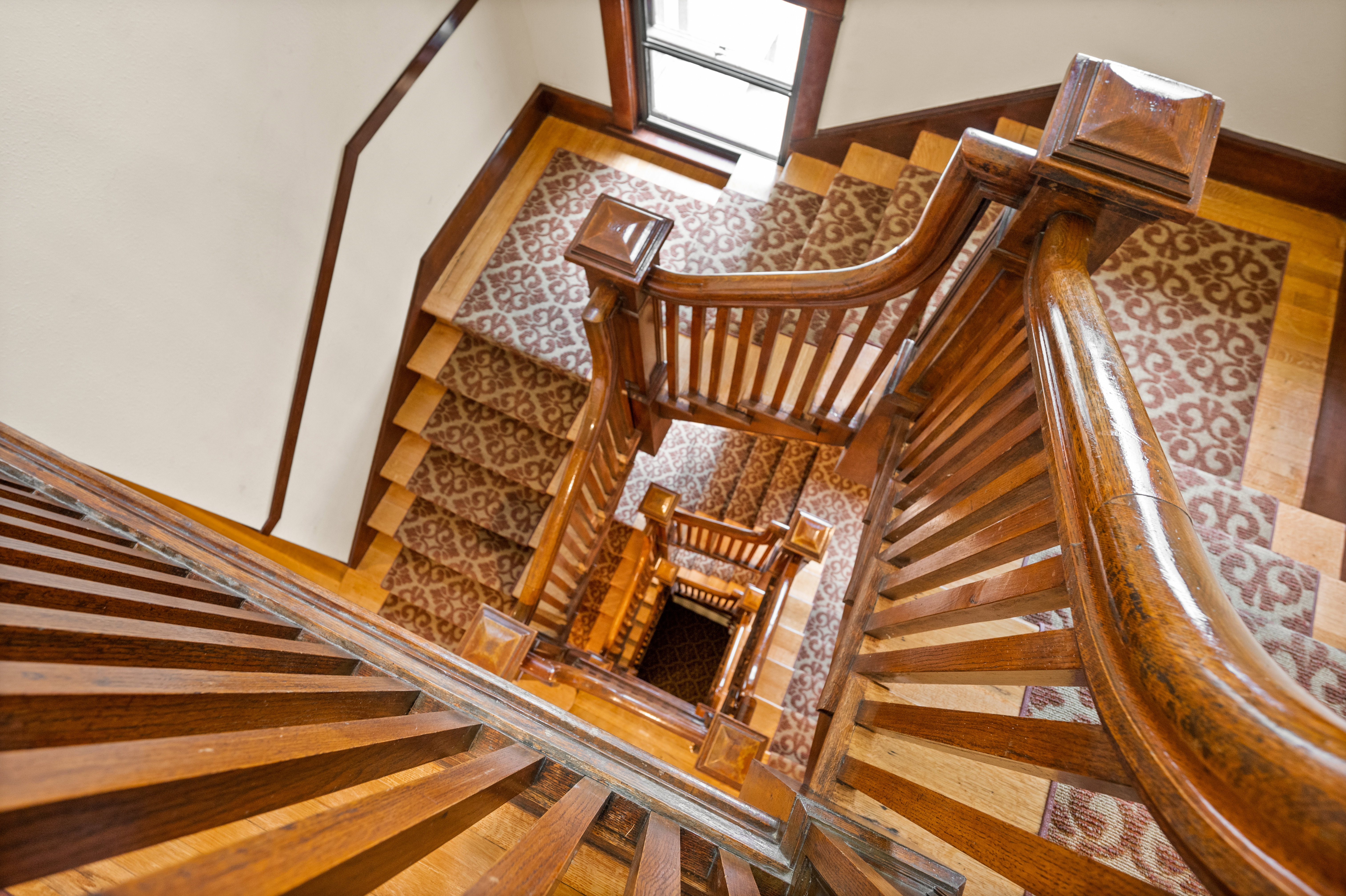 Ornate wood staircase featuring carved newel posts, turned balusters, and a curved handrail