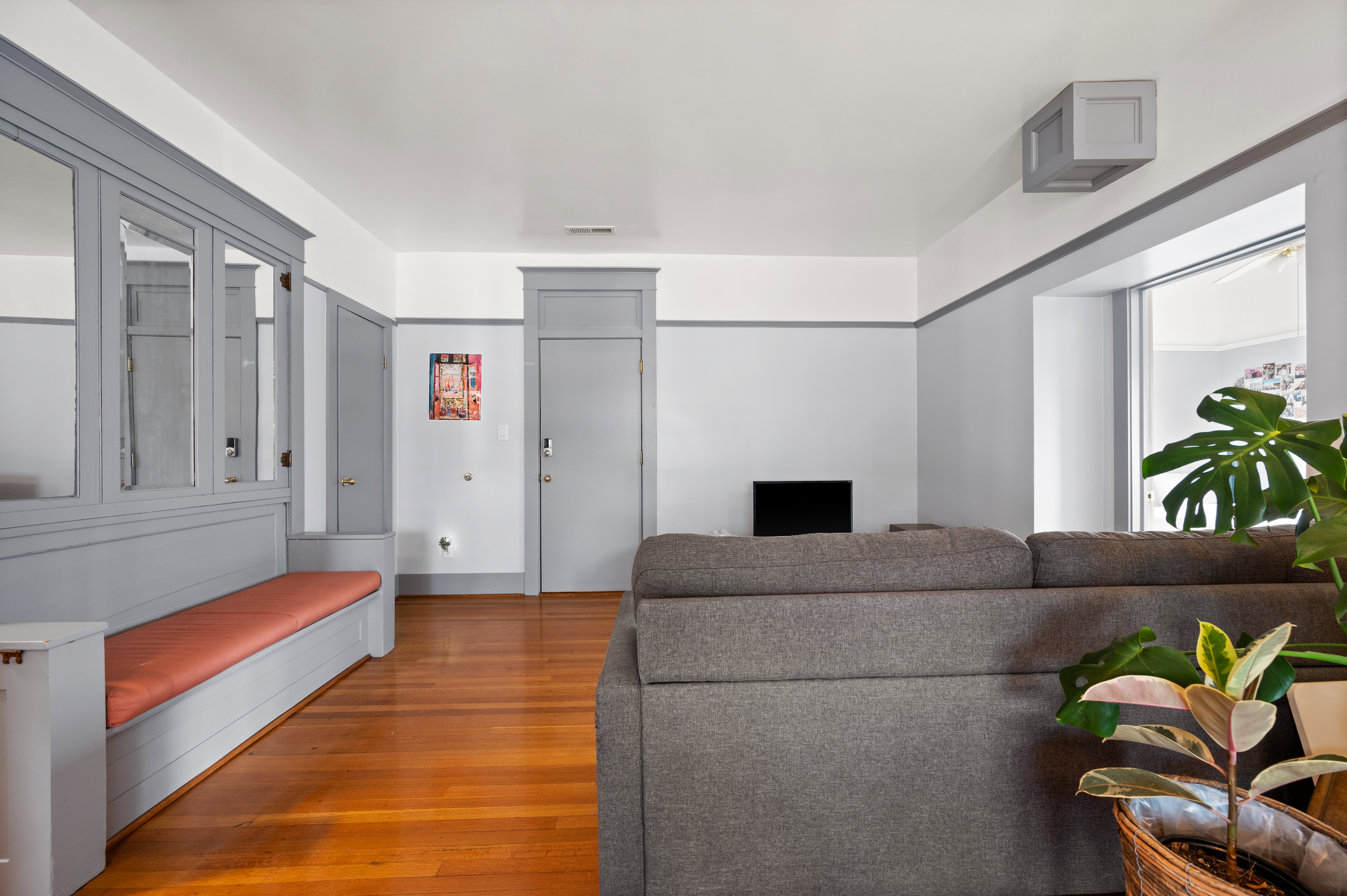 Living area featuring wood-finish flooring, a built-in bench with upholstered seating, and a large window