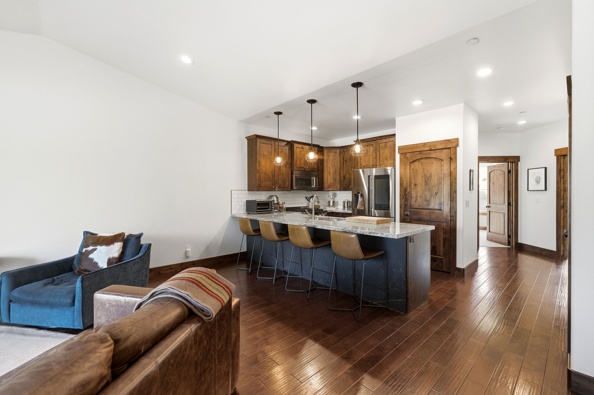 Open-concept kitchen featuring dark wood cabinetry, stainless steel appliances, a center island with bar seating, and pendant lighting