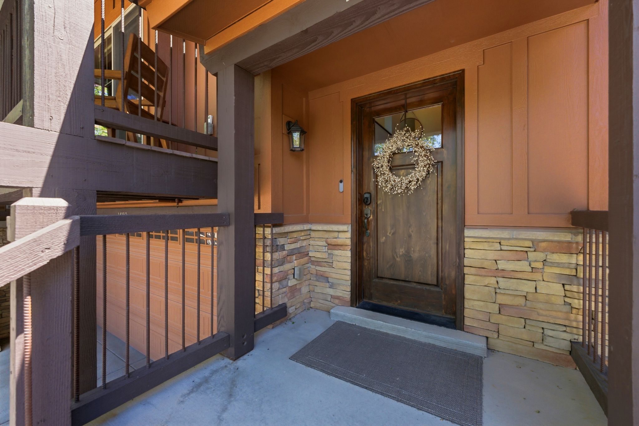 Entryway featuring a wood-panel door with glass inset, stacked stone accents, and a covered porch