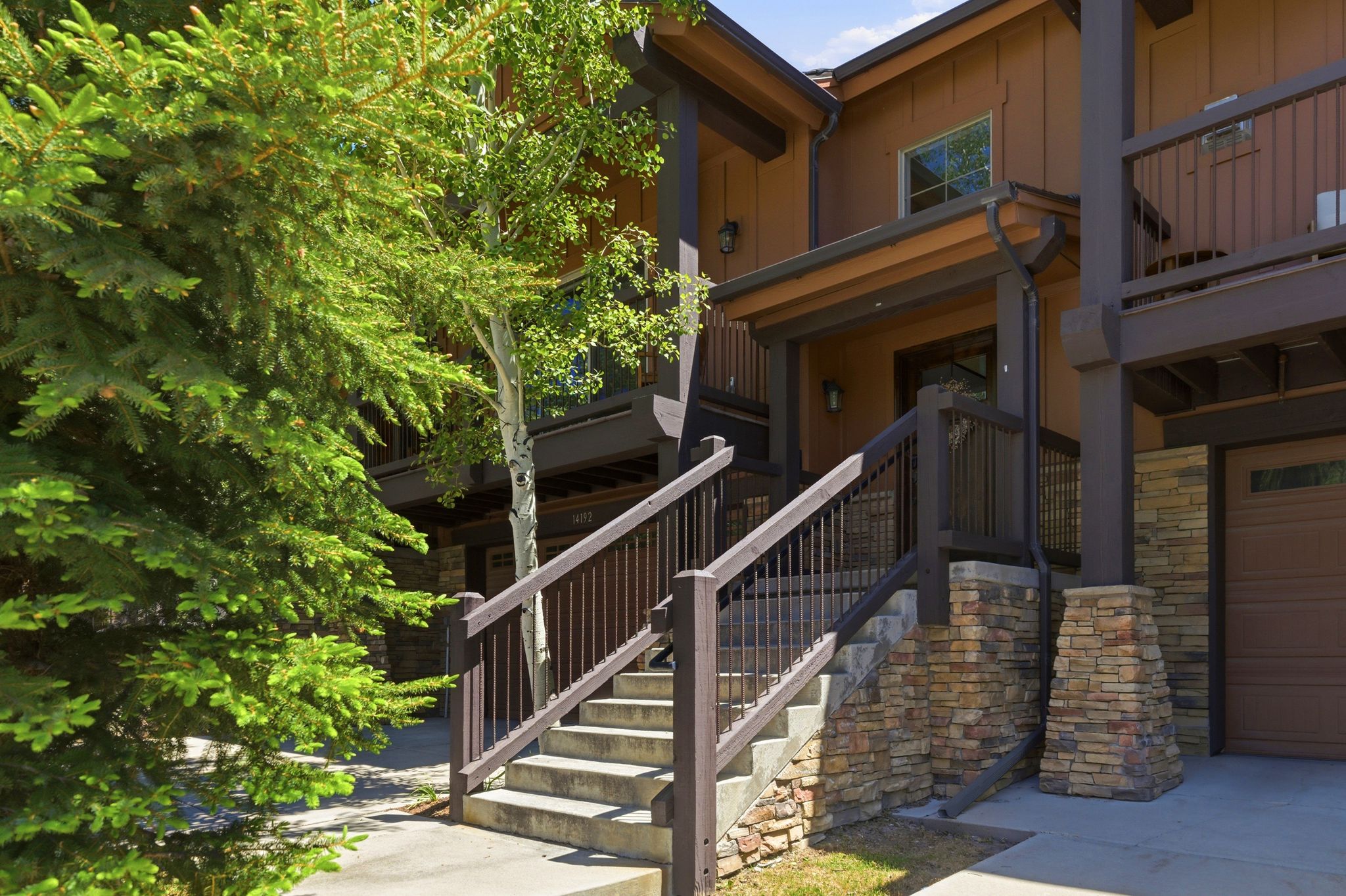 Multi-level exterior featuring stacked stone accents, a private garage, and a covered entry