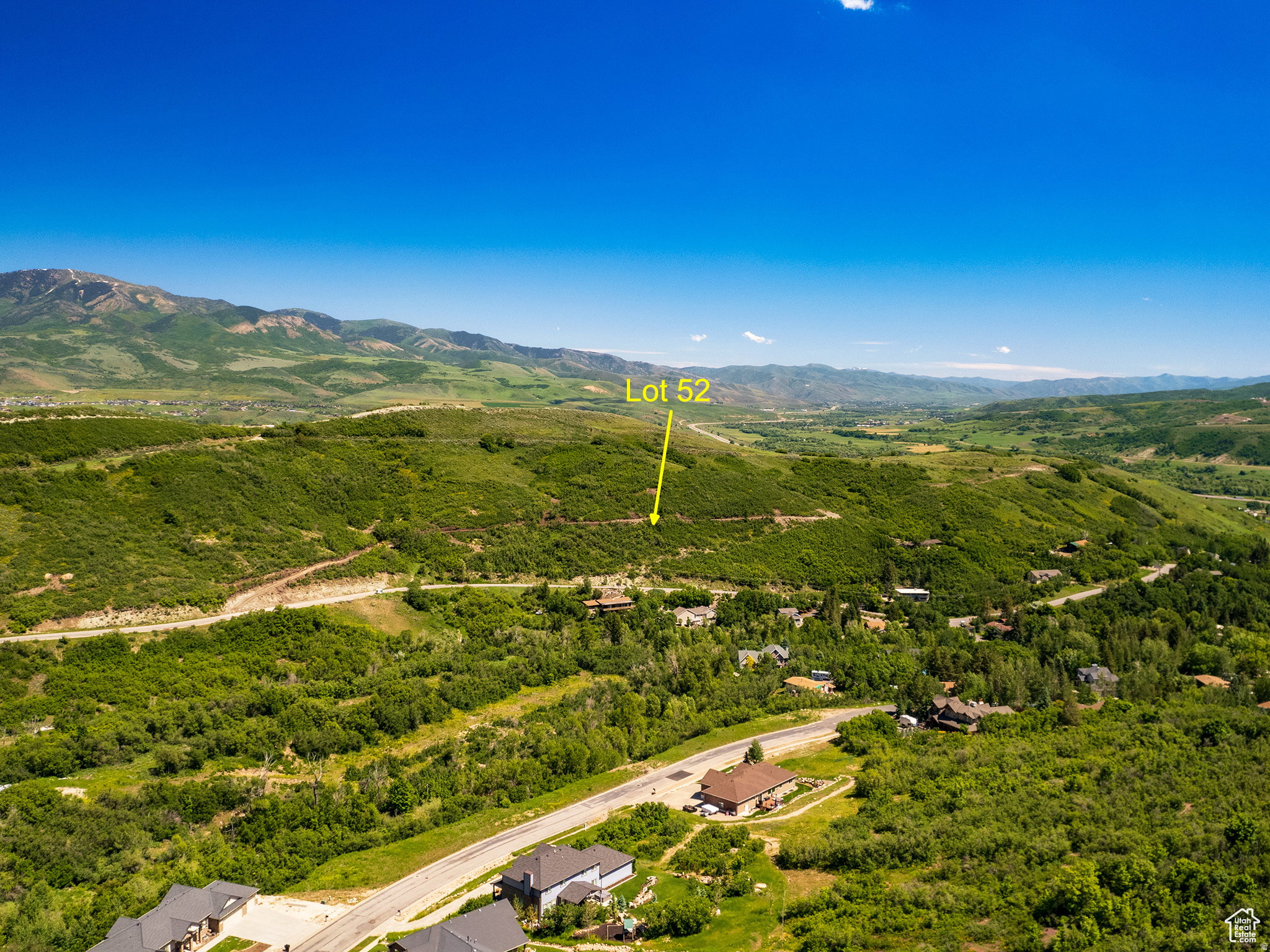 Expansive Lot 52, situated on a verdant hillside, offers a mountain backdrop and distant valley scenery