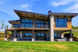 Modern mountain-style residence featuring a multi-level design and a combination of natural wood siding and stone accents