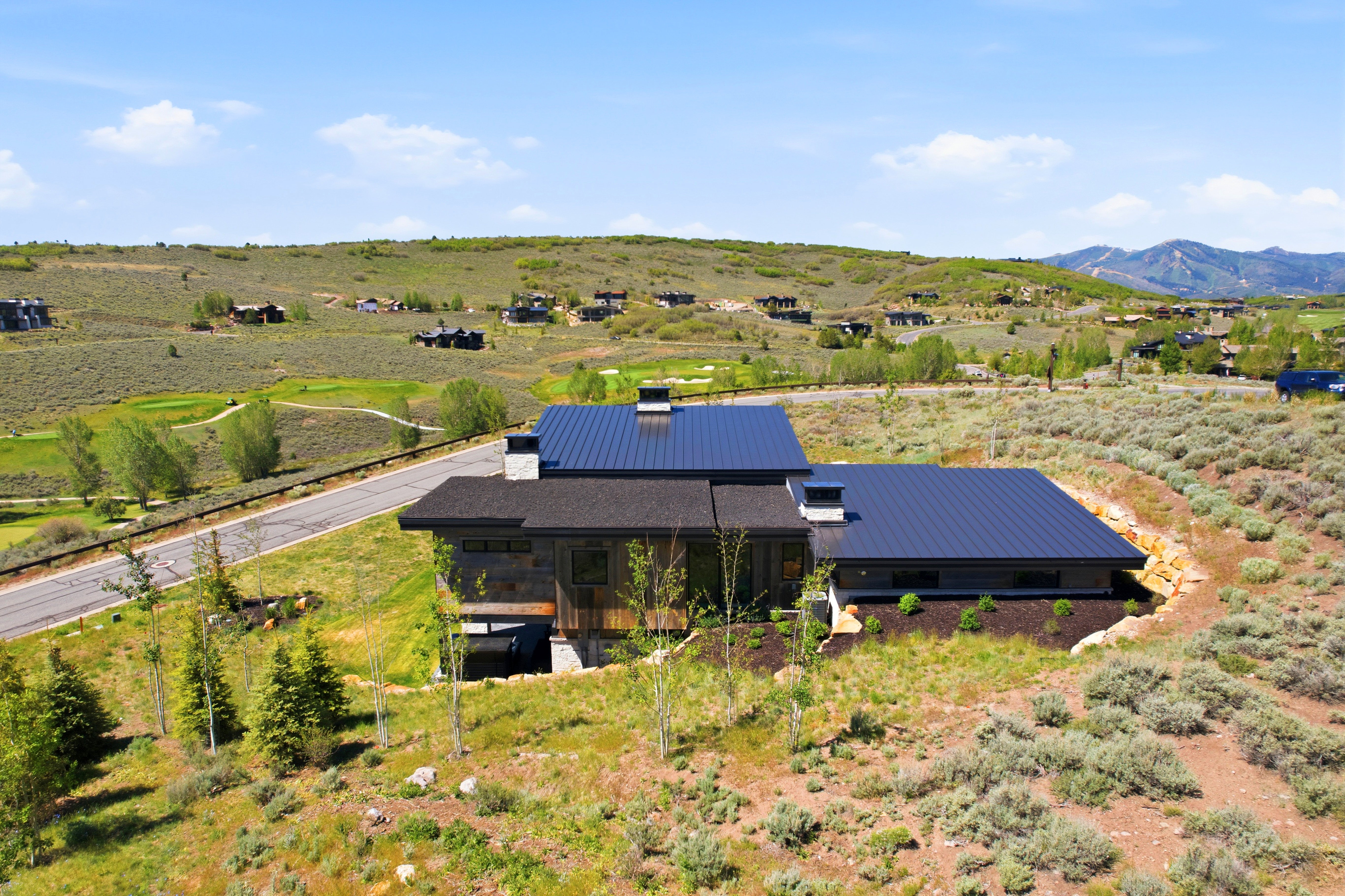 Modern-style residence featuring a dark metal roof, natural wood siding, and stone accents