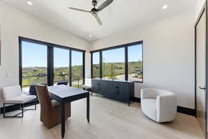 Bright interior space featuring expansive windows, light wood-finish flooring, a contemporary ceiling fan, recessed lighting, and a built-in dark wood console
