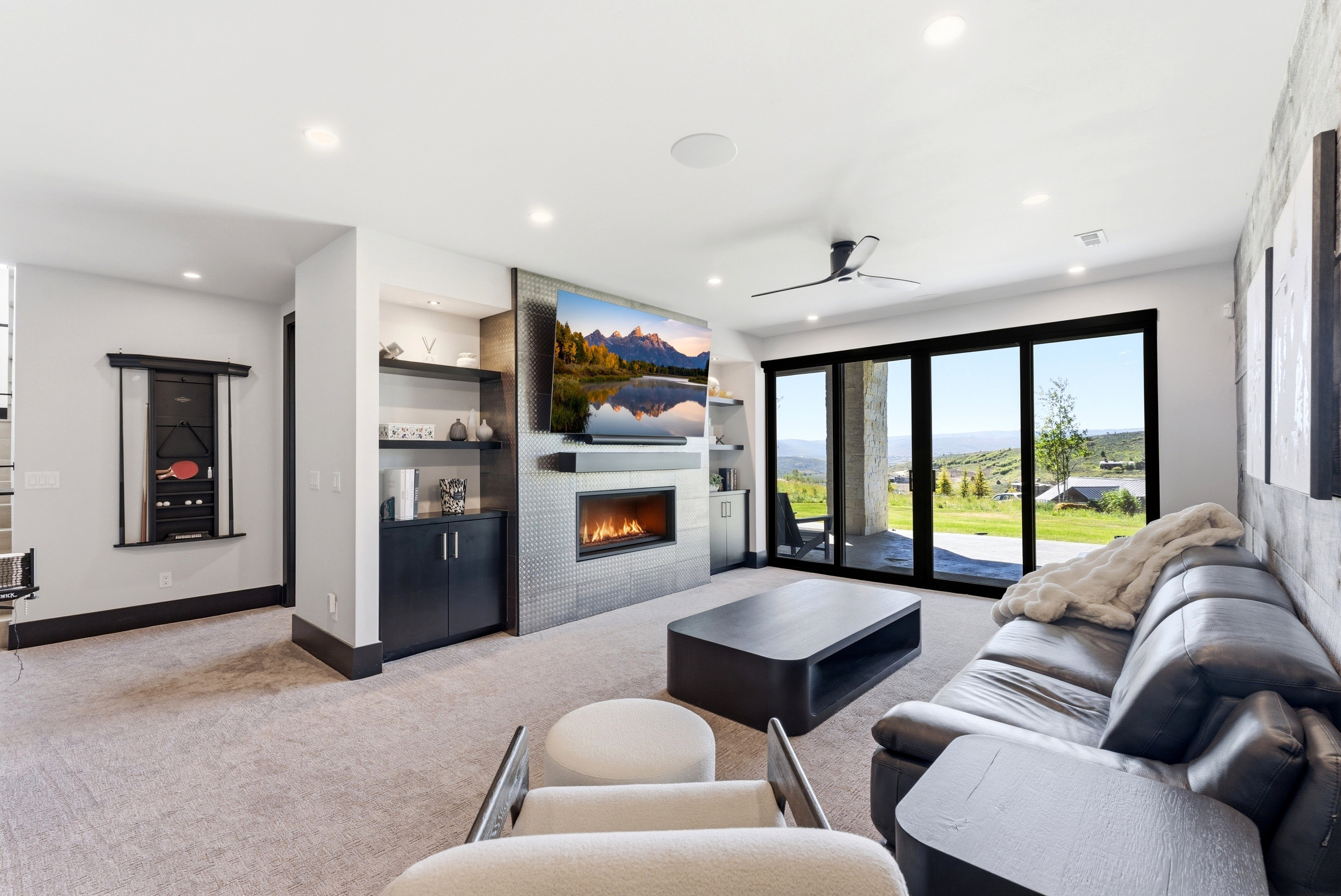 Living area featuring a contemporary fireplace with a tiled surround, built-in shelving, and direct patio access through large glass sliding doors