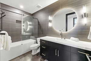 Bathroom featuring a deep soaking tub with glass shower enclosure, a dark wood-finish vanity with a white countertop, a circular back-lit mirror, and modern wall sconces