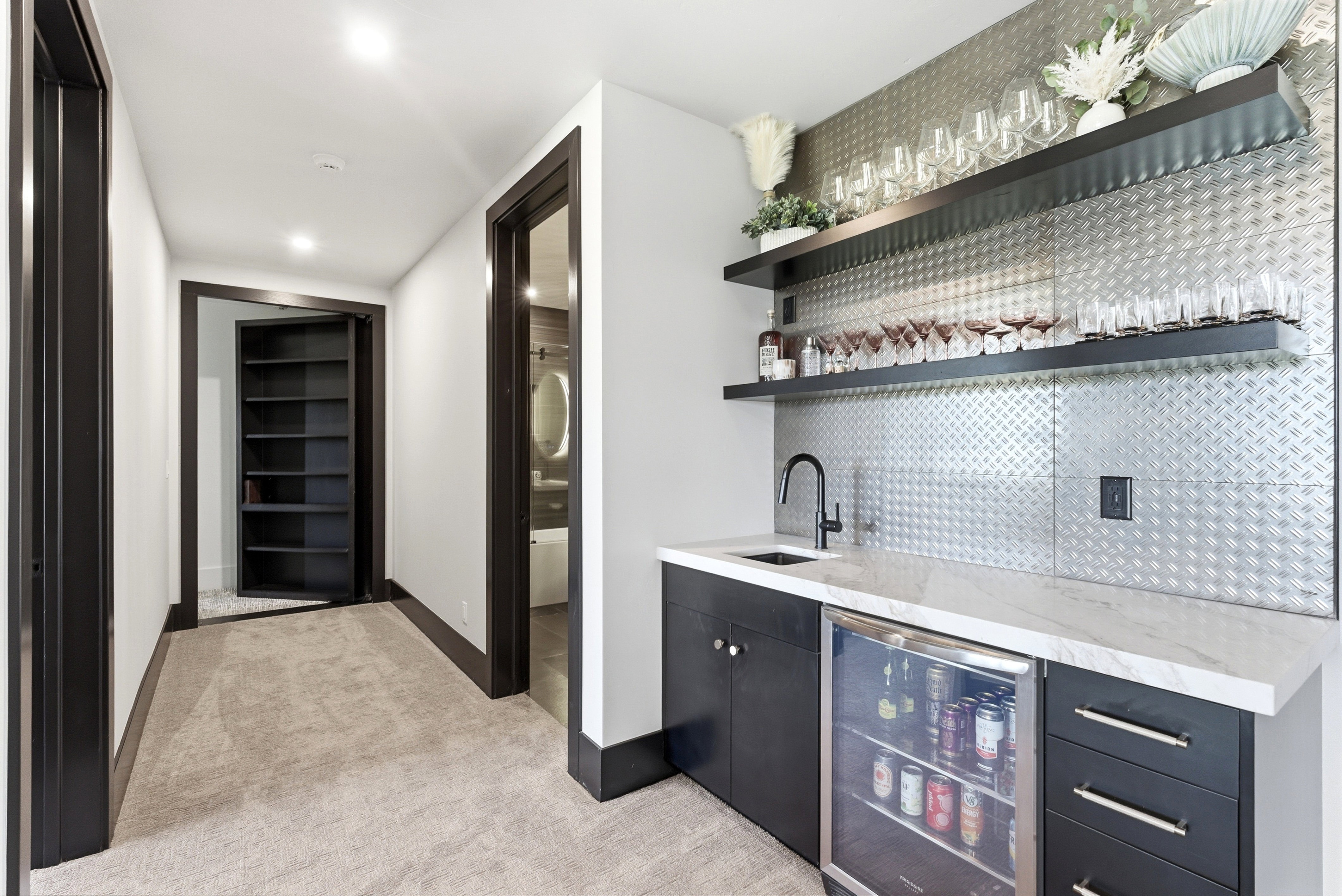 Wet bar featuring a mini-refrigerator, dark cabinetry, and a light-toned countertop