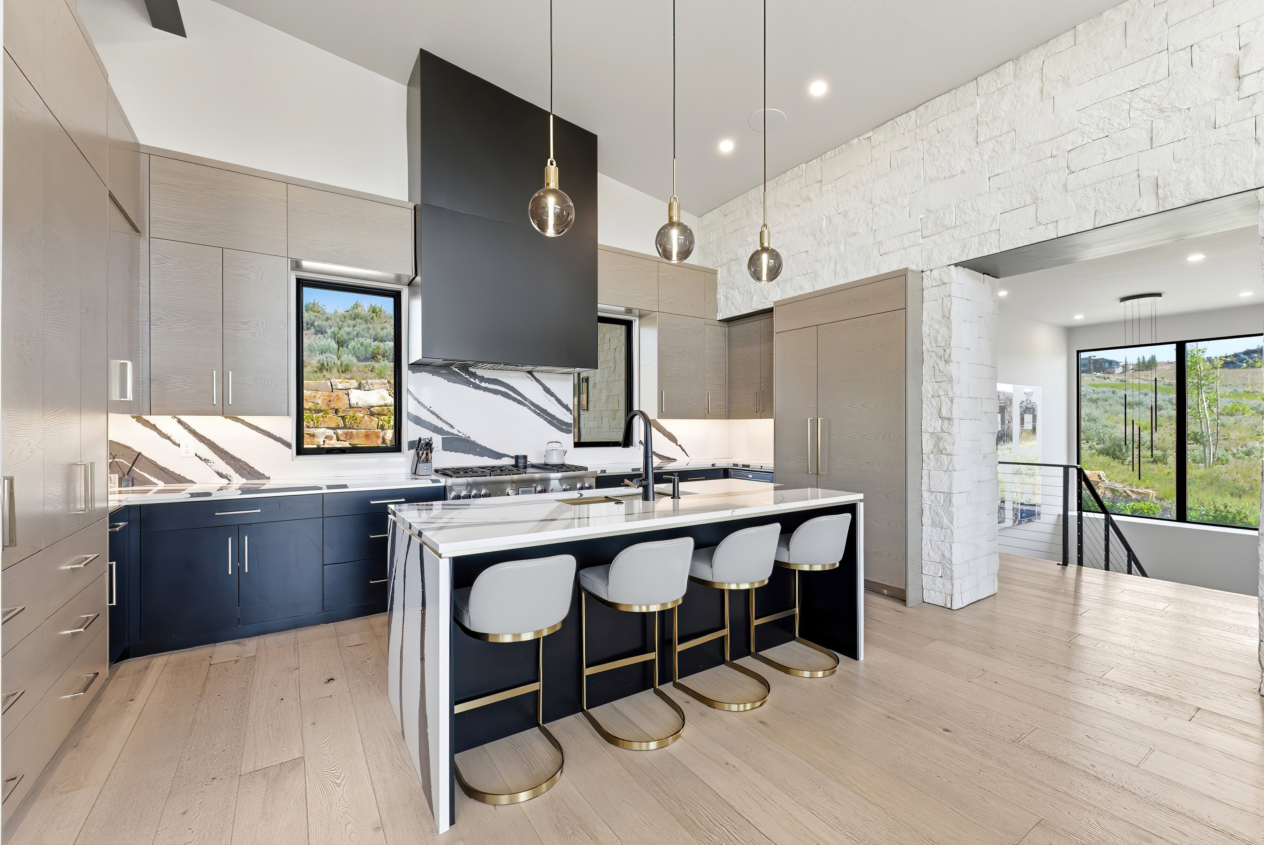 Modern kitchen featuring light wood-finish flooring, a large island with a waterfall countertop, and integrated appliances