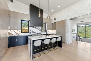 Modern kitchen featuring light wood-finish flooring, a large island with a waterfall countertop, and integrated appliances