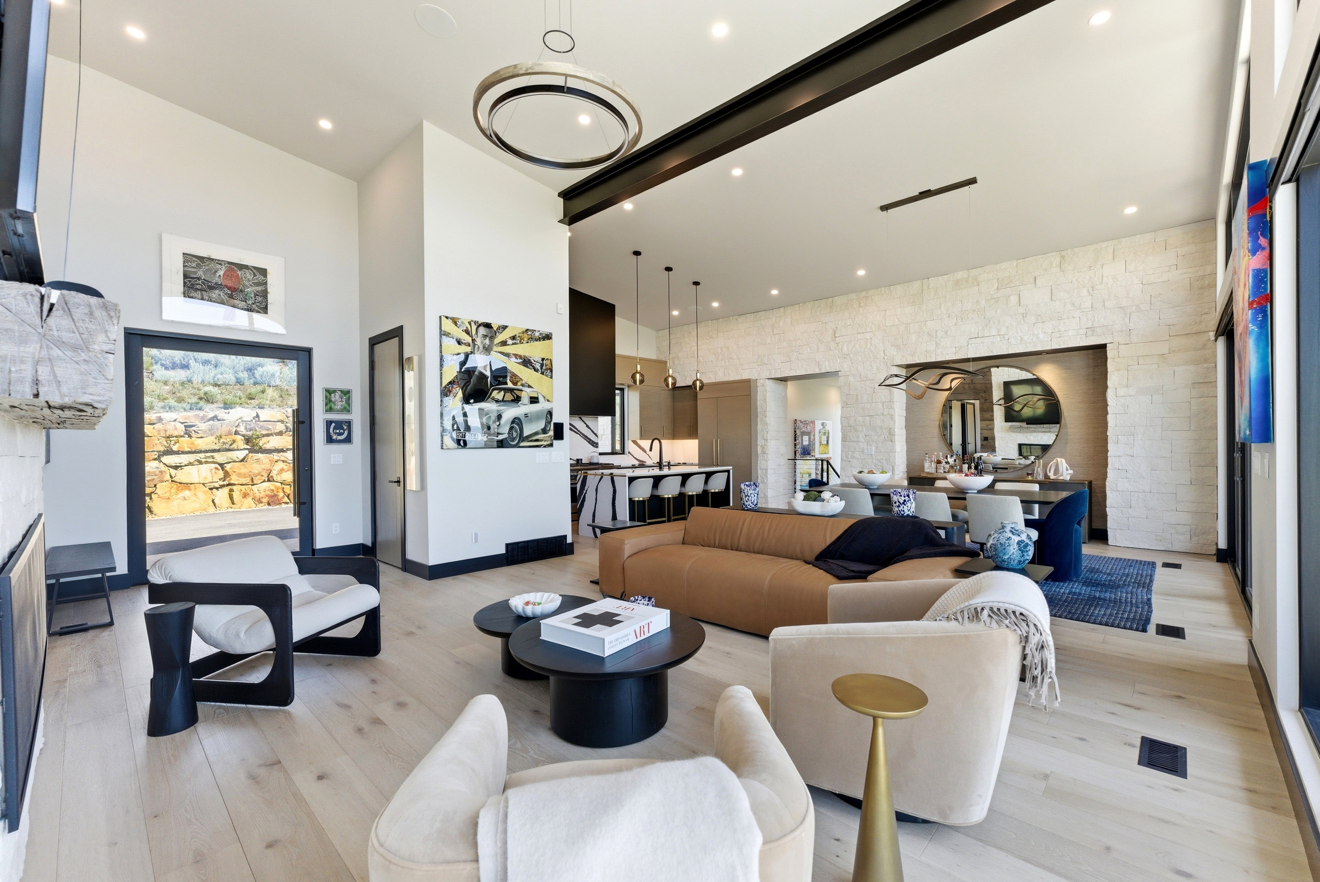 Expansive open-concept living space featuring high ceilings, light wood-finish flooring, and a stone accent wall