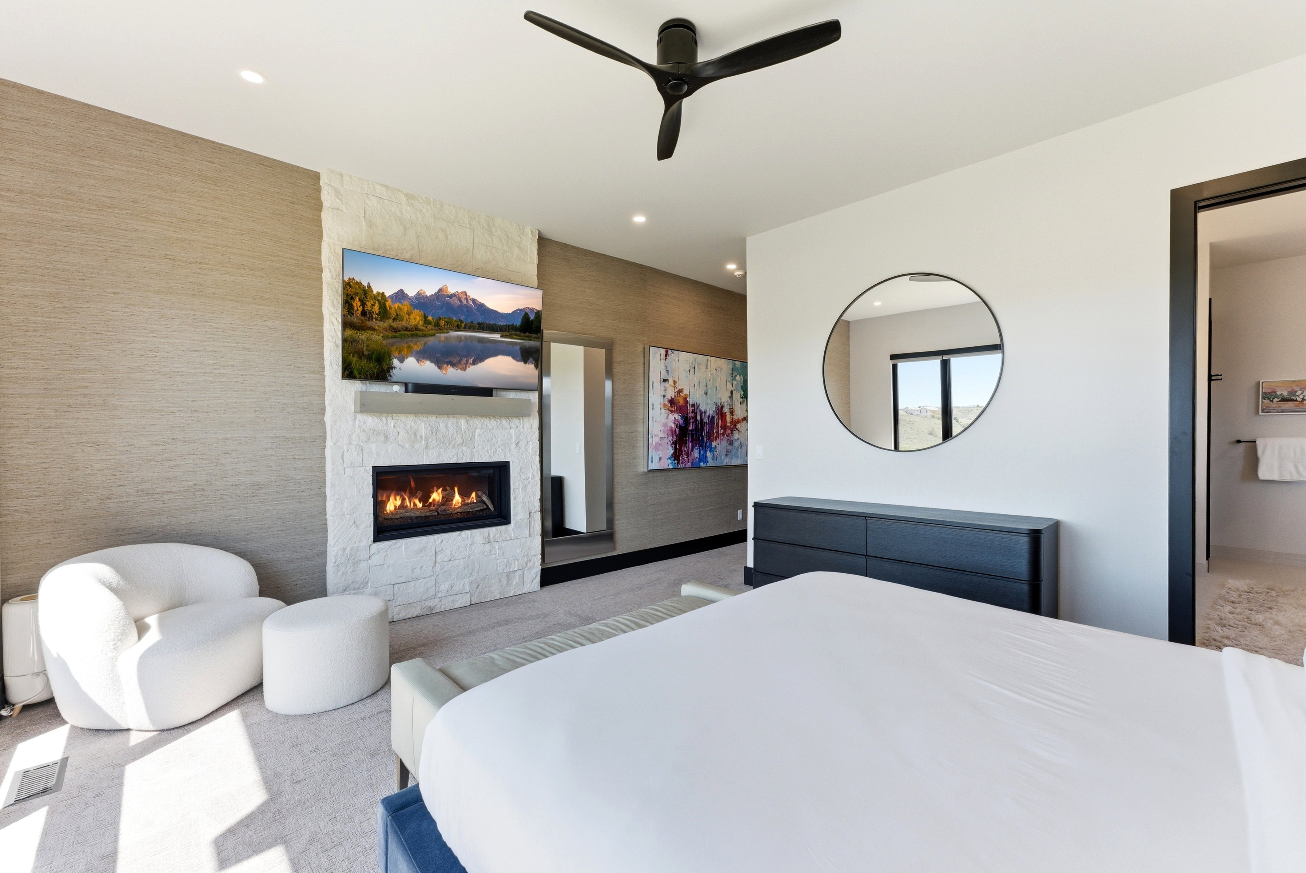 Modern bedroom featuring a built-in fireplace with a stacked stone facade and a wall-mounted television