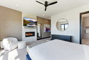 Modern bedroom featuring a built-in fireplace with a stacked stone facade and a wall-mounted television