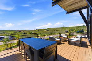 Expansive outdoor deck featuring composite decking, glass panel railing, and a slatted wood ceiling
