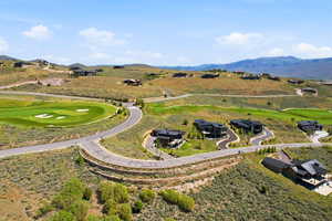 Expansive golf course community featuring winding roads, multiple contemporary residences, and distant mountain ranges