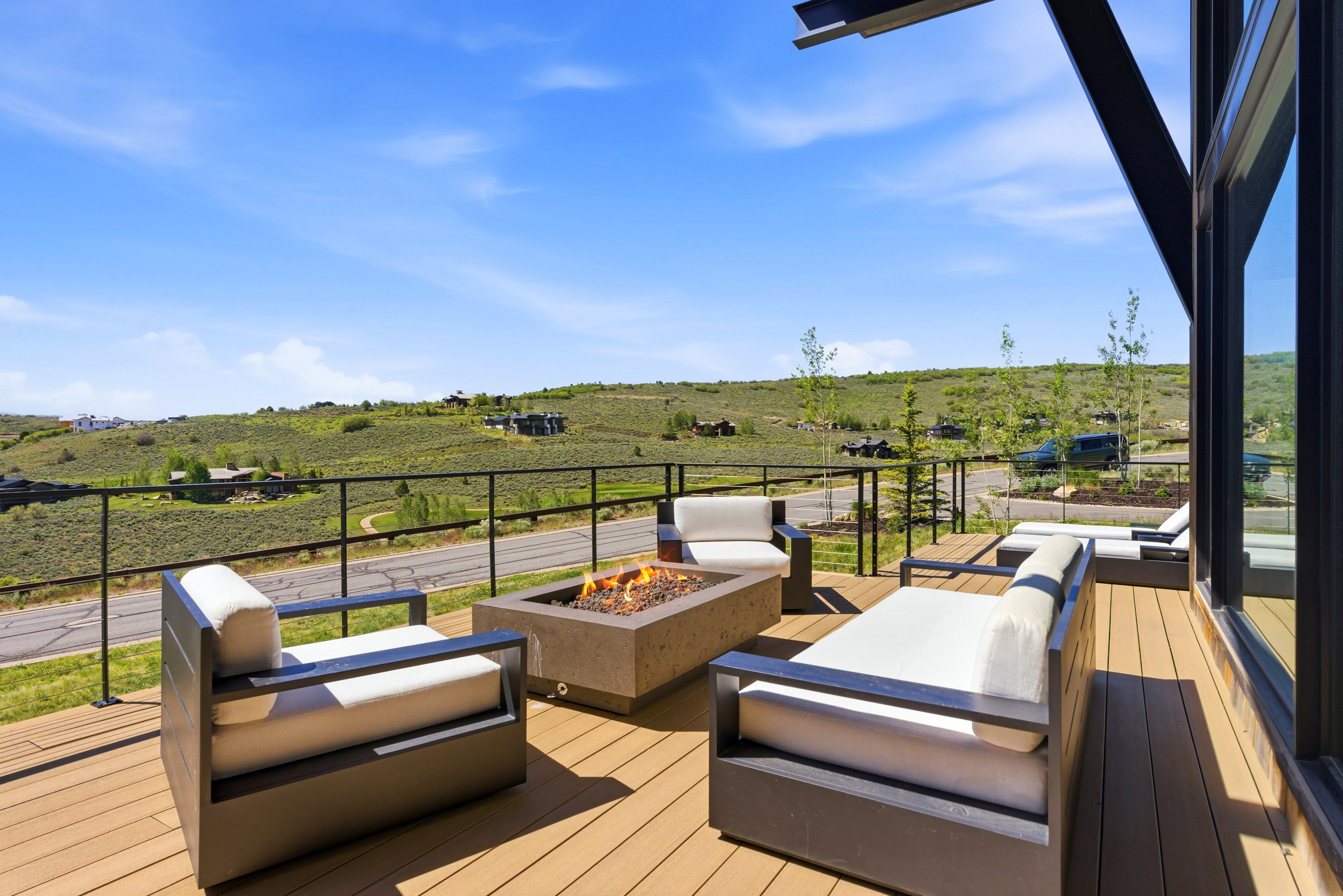 Expansive outdoor deck featuring wood-finish decking, a built-in fire pit, and black metal railings