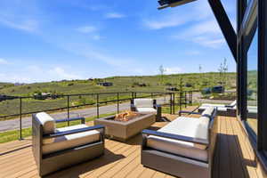 Expansive outdoor deck featuring wood-finish decking, a built-in fire pit, and black metal railings