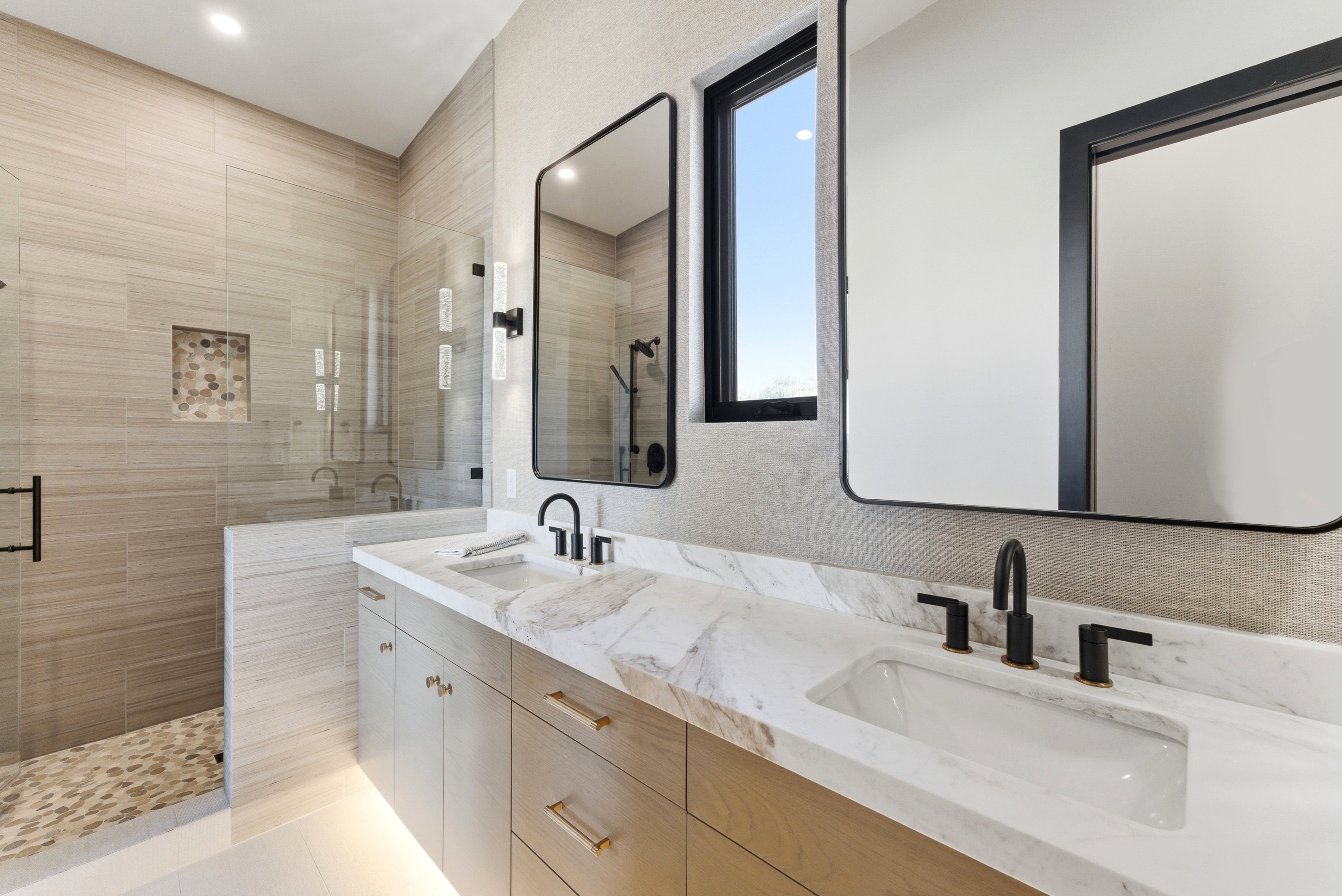 Double vanity featuring integrated sinks, matte black fixtures, and a marbled countertop