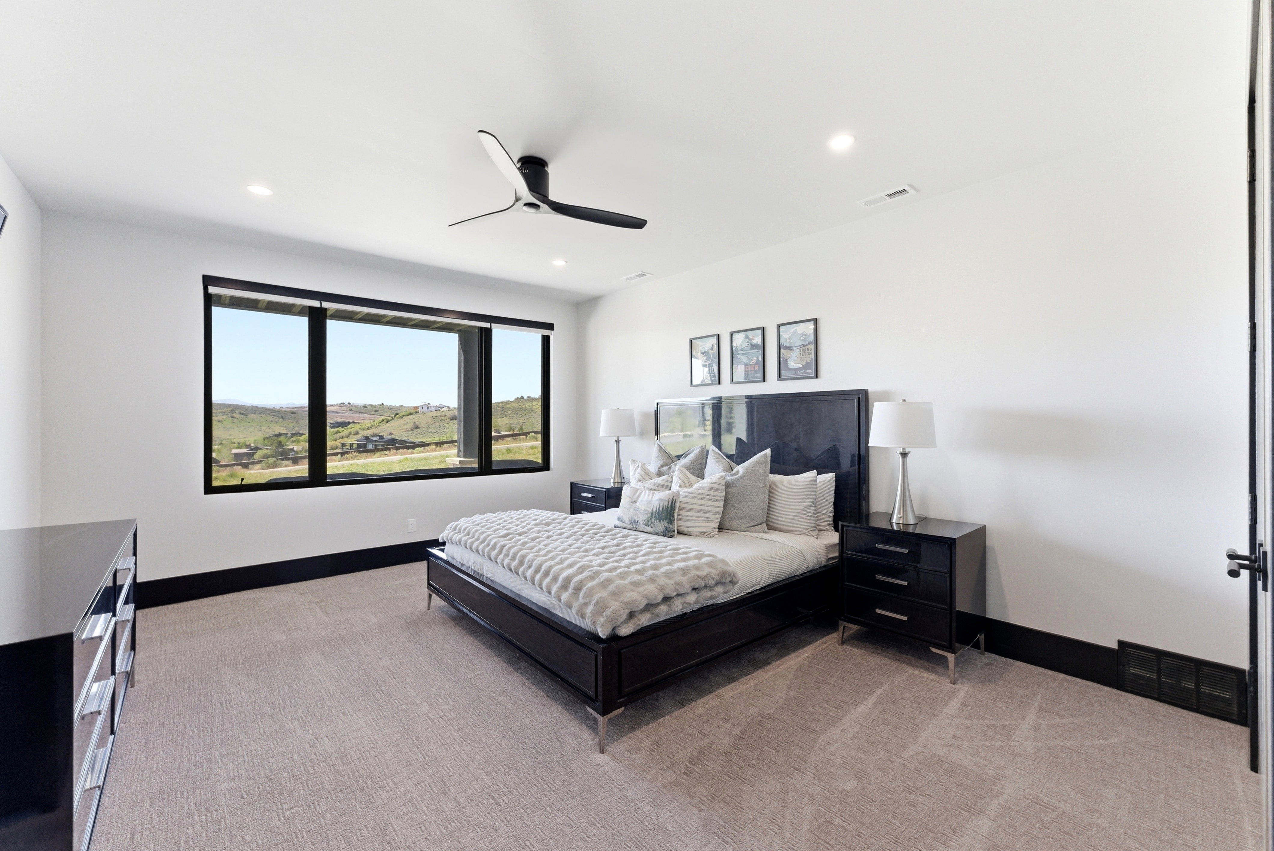 Expansive window with black trim framing hillside scenery