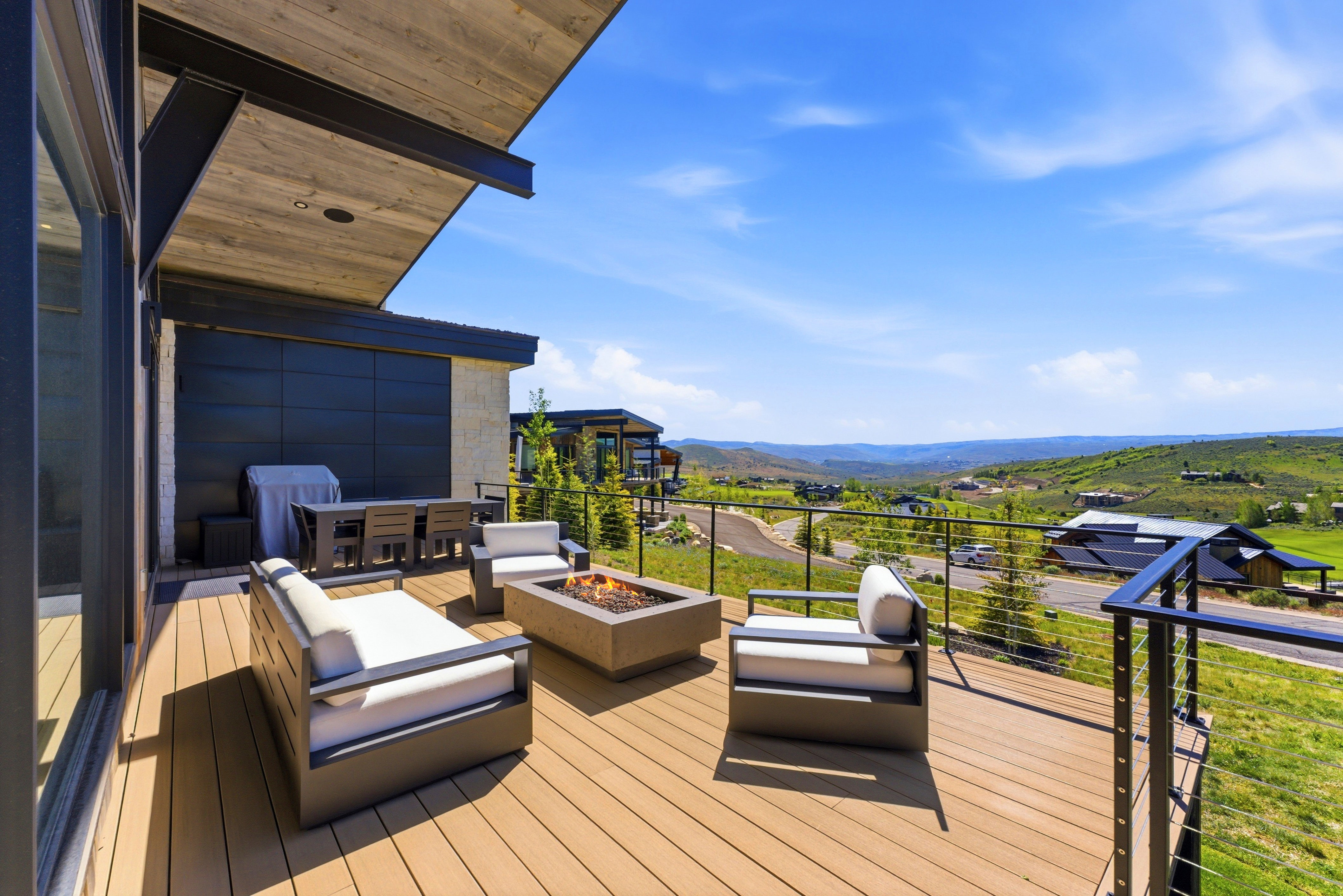 Expansive outdoor deck featuring composite decking, a built-in fire pit, and cable railing