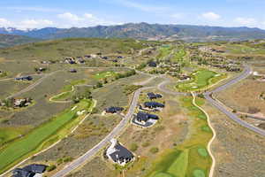 Expansive mountain landscape featuring a golf course, residential properties, paved roadways, and distant snow-capped mountains