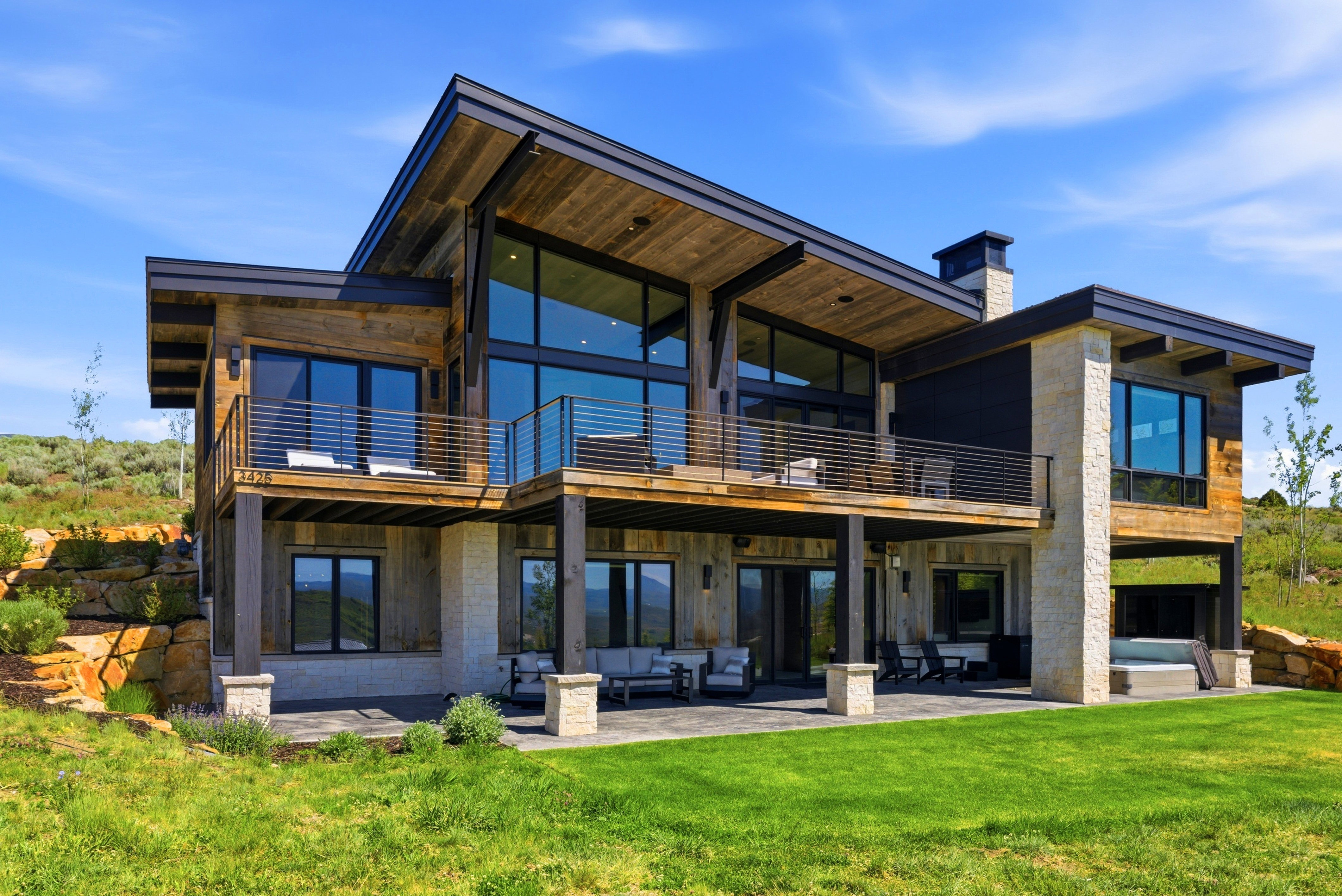 Modern architectural design featuring expansive glass panels, wood-finish siding, and stone accents