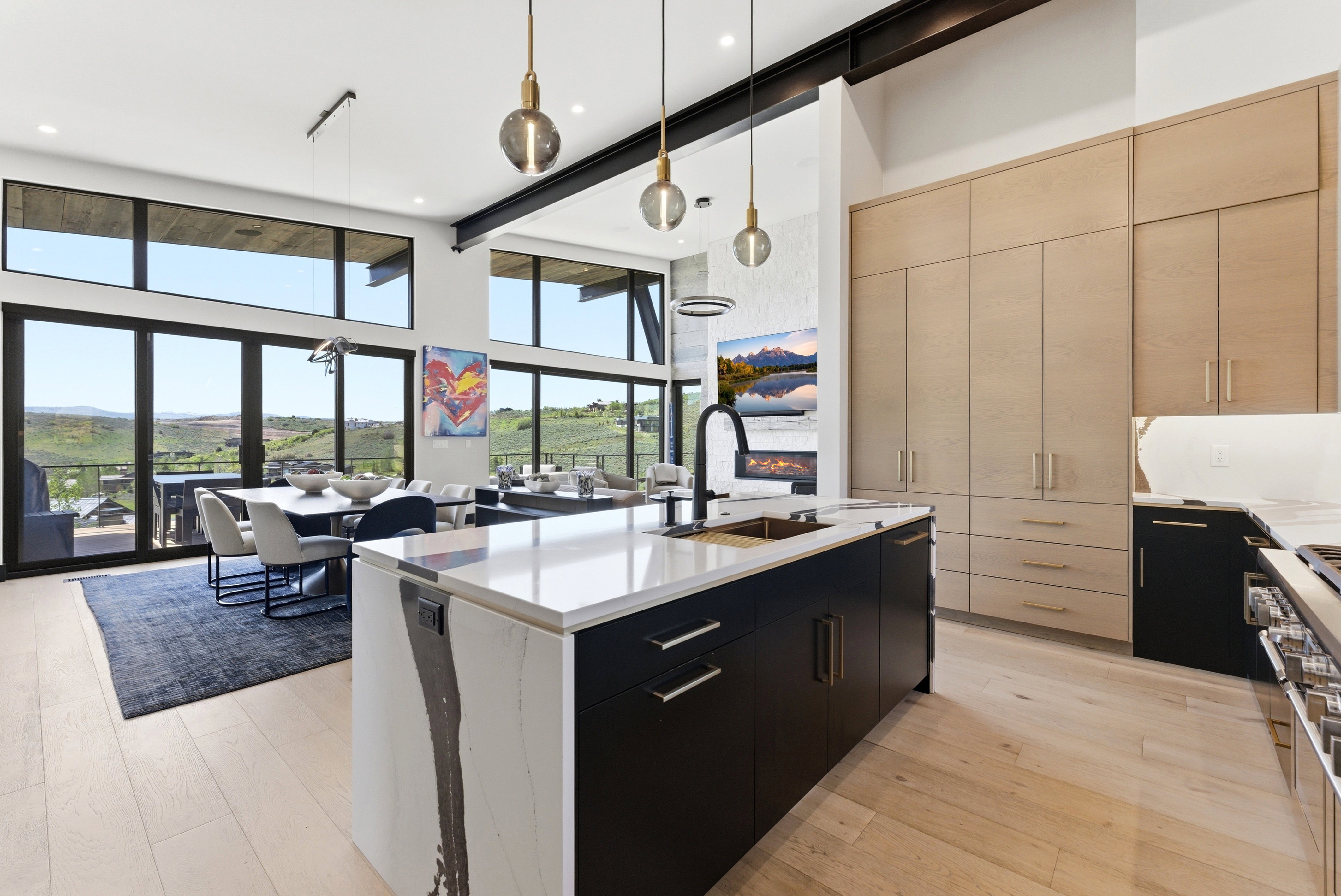 Expansive kitchen and dining area featuring a large center island with a waterfall countertop, integrated sink, and matte black faucet