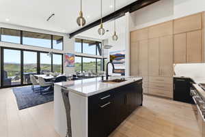 Expansive kitchen and dining area featuring a large center island with a waterfall countertop, integrated sink, and matte black faucet