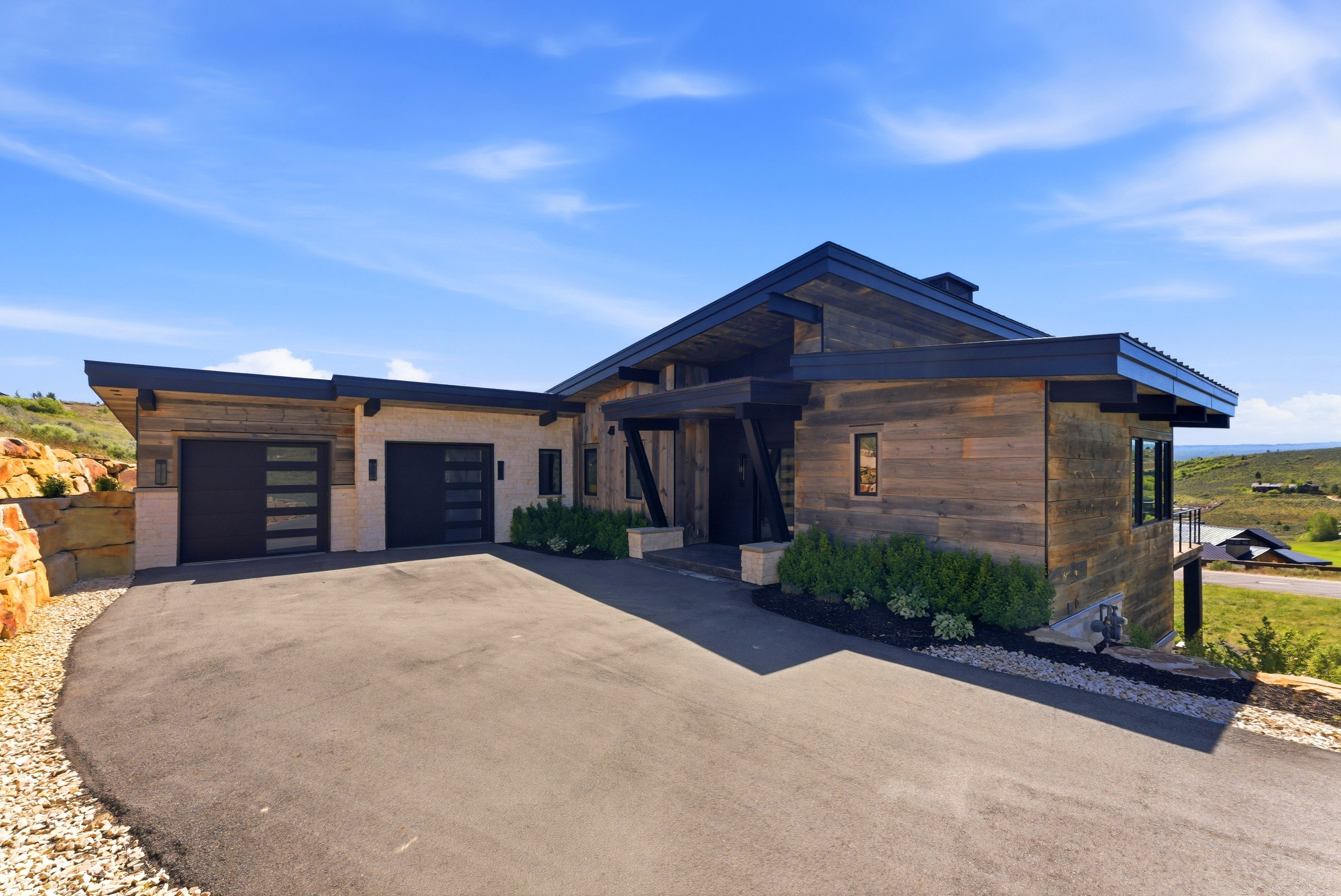Modern architectural residence featuring multi-tone wood siding and light-toned stone accents