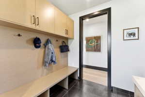 Built-in wooden cabinetry with matte black hardware, integrated bench seating, and wall-mounted hooks