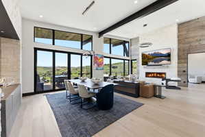 Expansive open-concept room featuring wide plank wood-finish flooring, a contemporary linear fireplace with a stone surround, and floor-to-ceiling windows with a transom
