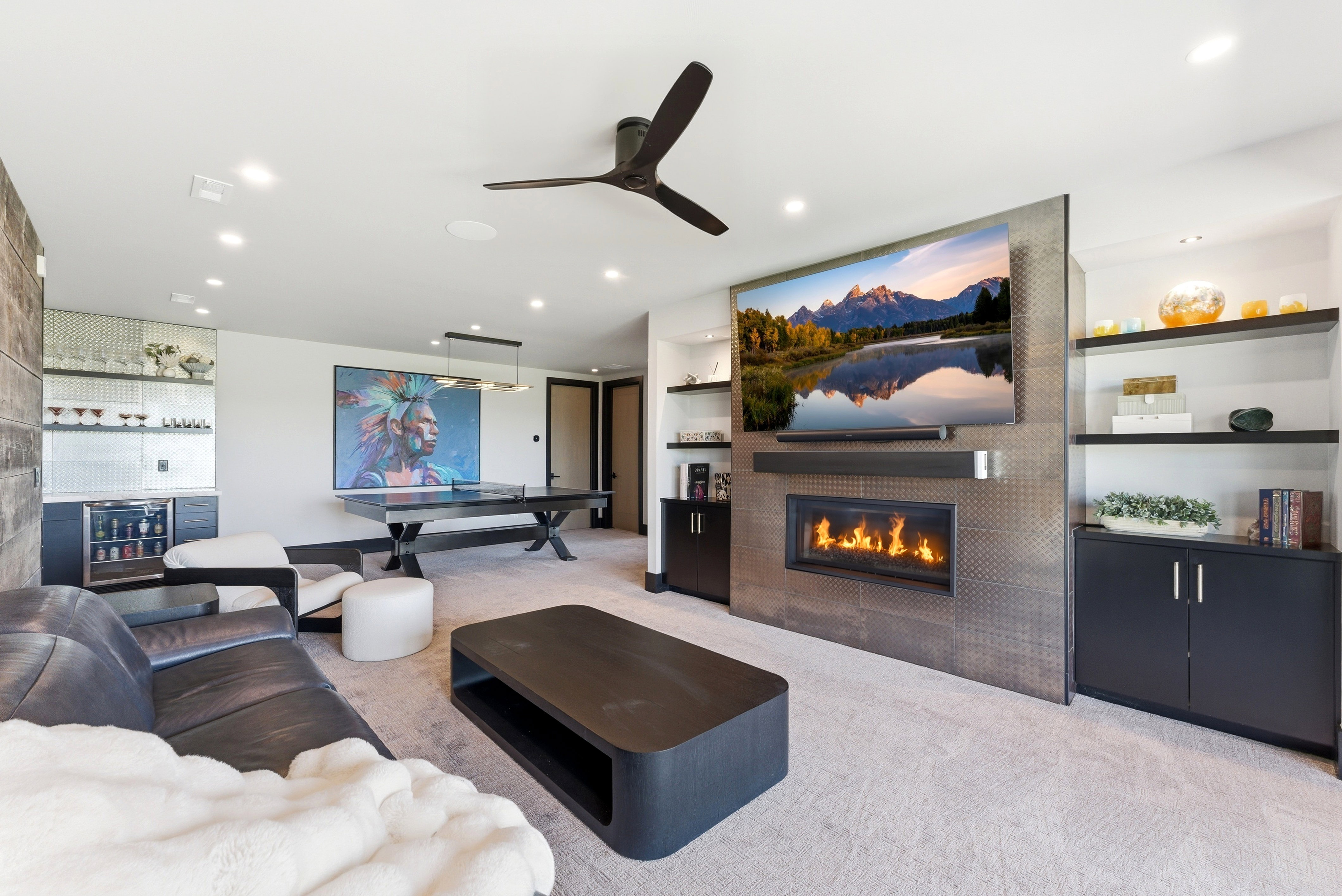 Entertainment room featuring a built-in fireplace with a textured surround, integrated shelving, and a wet bar with a beverage cooler