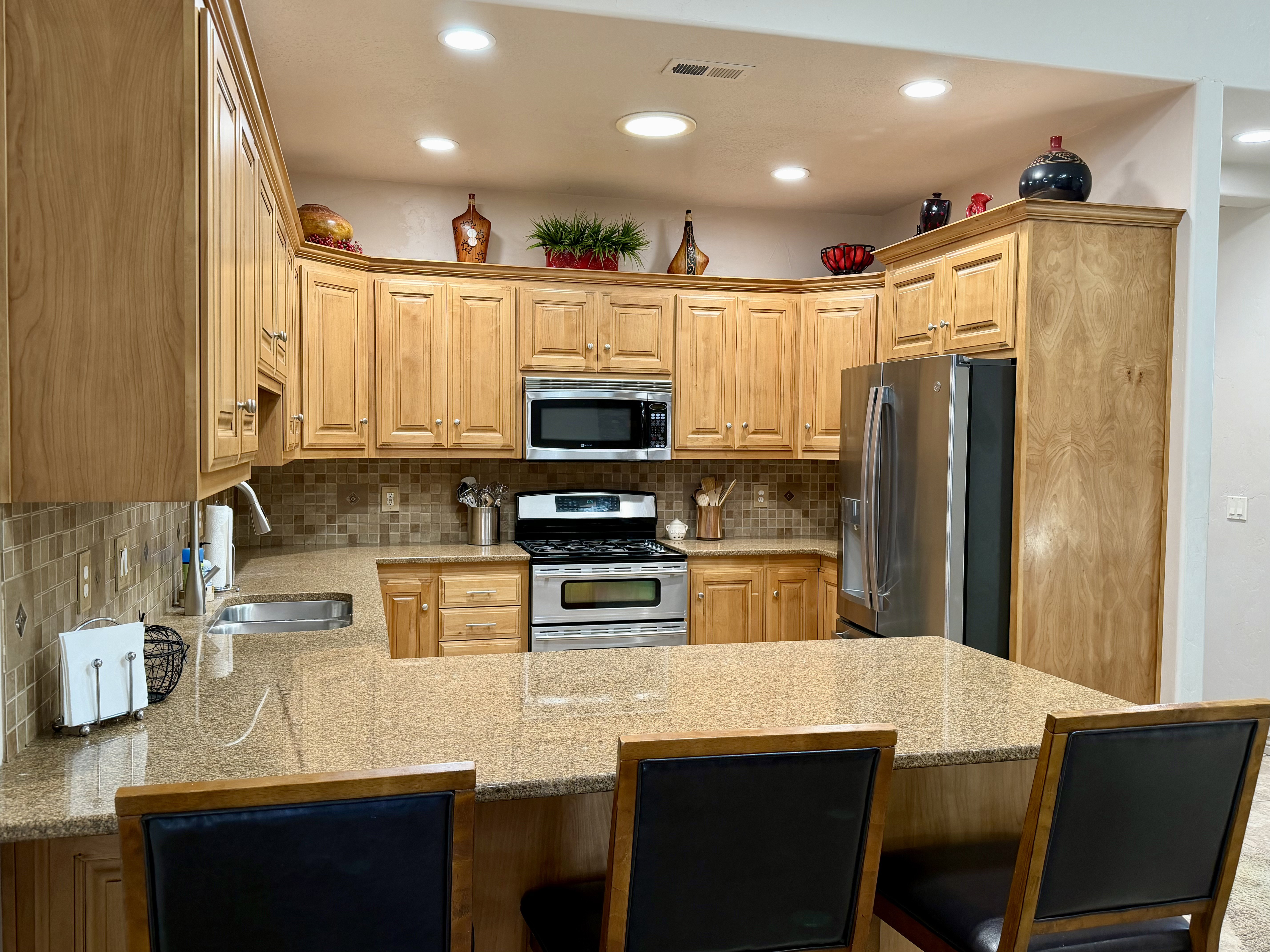 Warm and inviting kitchen features rich custom wood cabinetry, expansive granite countertops and stainless steel appliances for beauty and function, together with the stylish tile backsplash