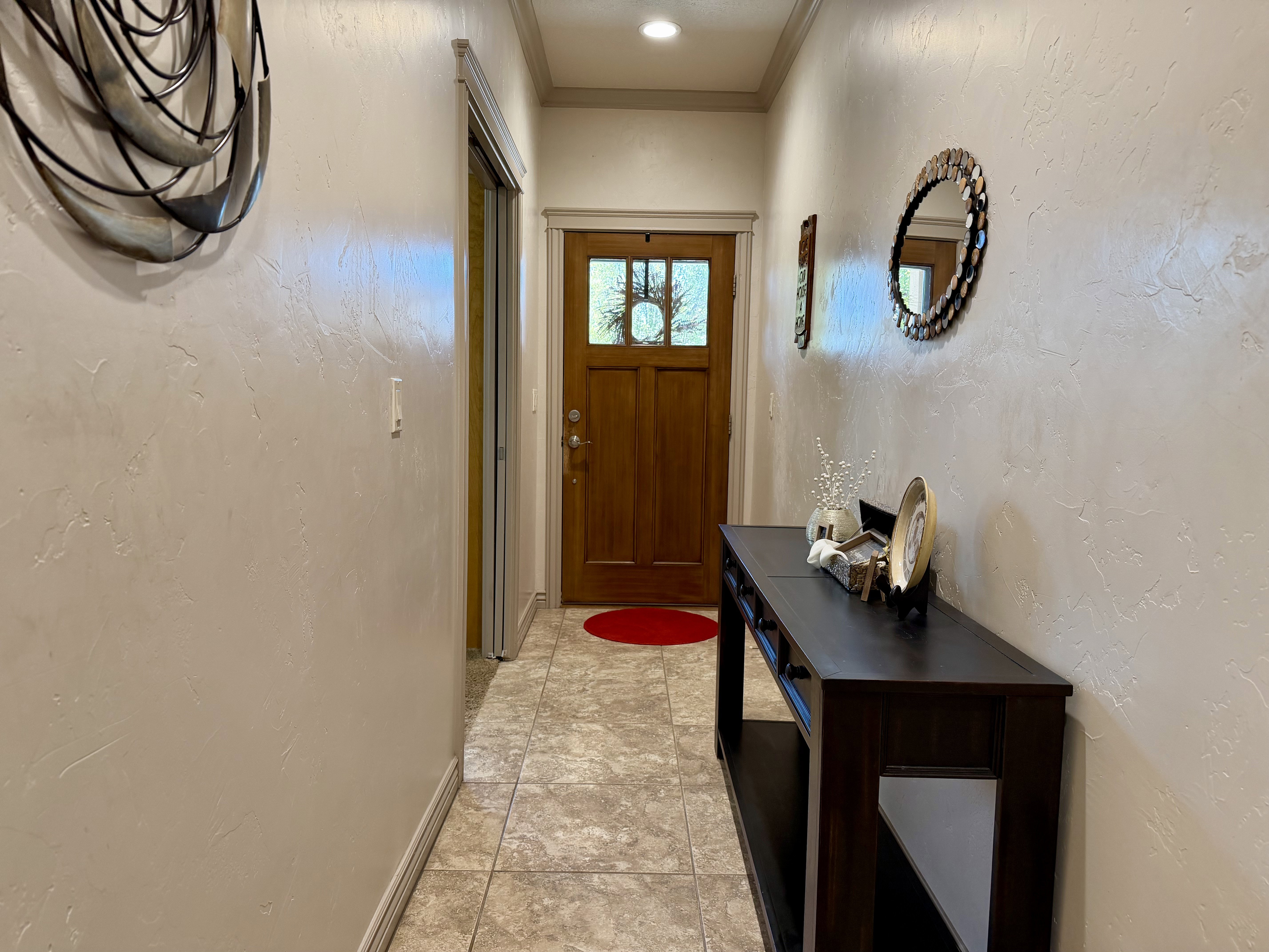 Entryway featuring a decorative wood-panel door, recessed lighting, crown molding, and neutral-toned tile flooring