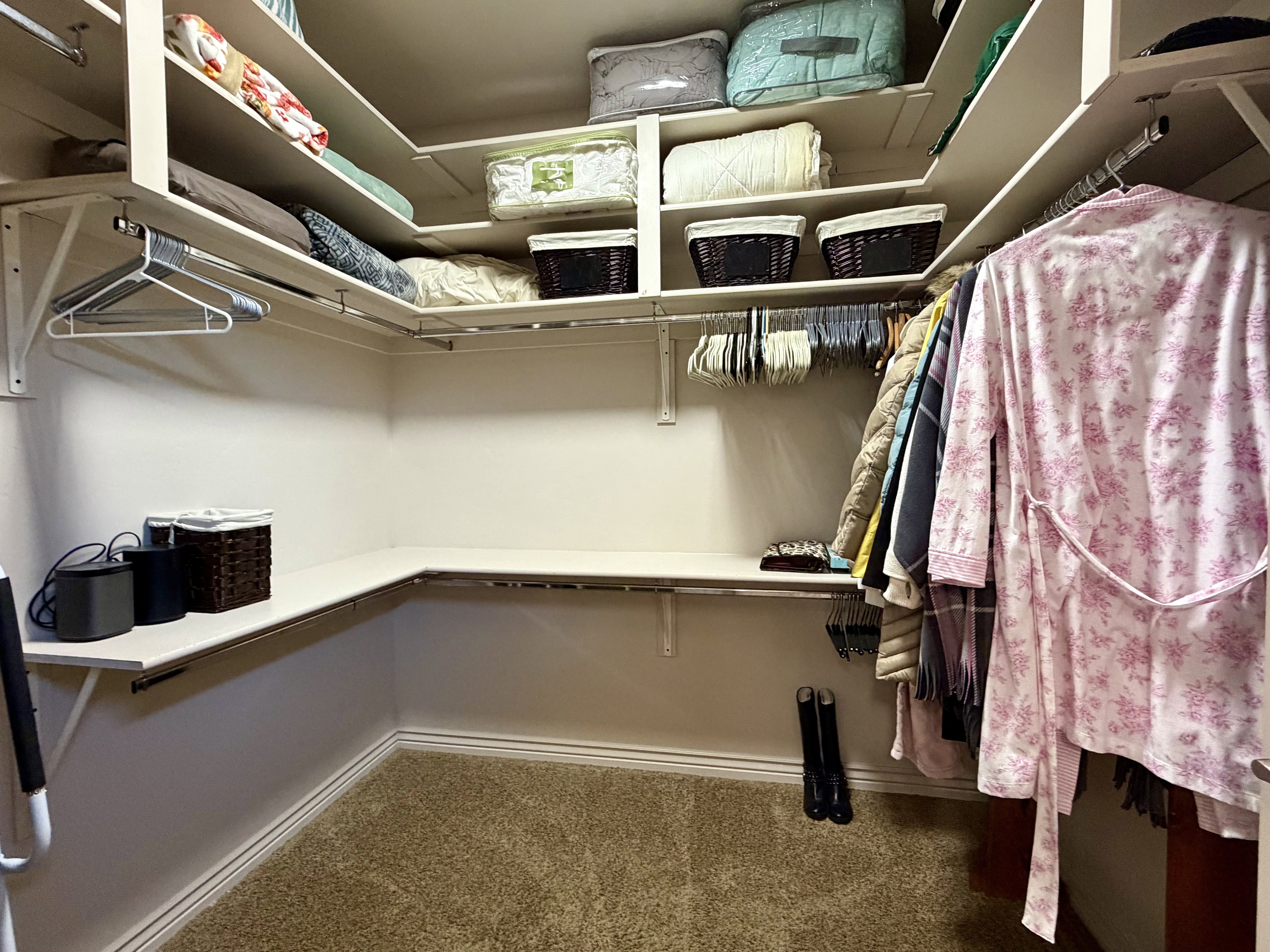 Mater bedroom walk-in closet featuring extensive built-in shelving, multiple hanging rods, and plush carpet flooring