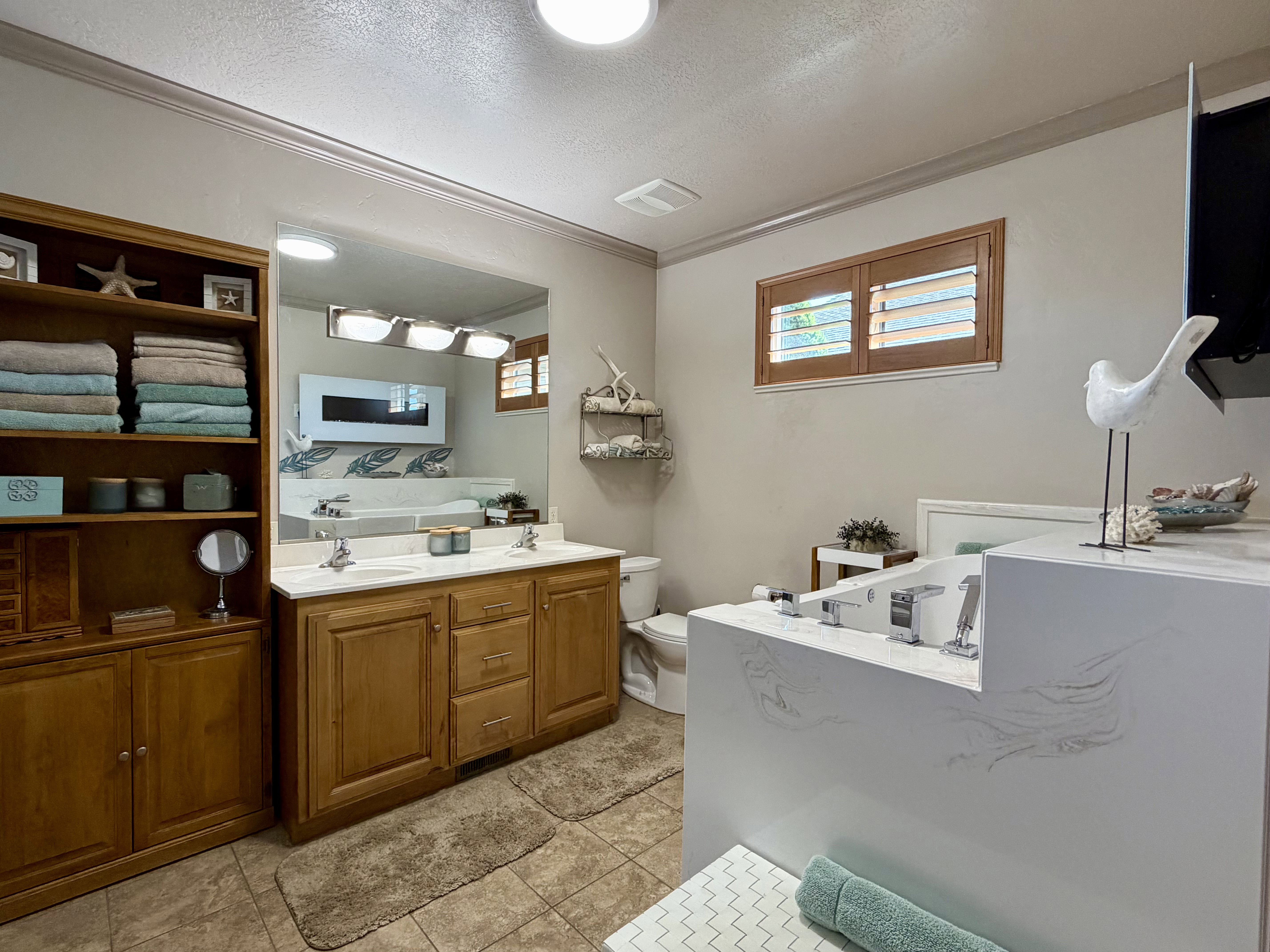 Spacious master bathroom featuring a double vanity with wood cabinetry and a large mirror abundant lighting and storage