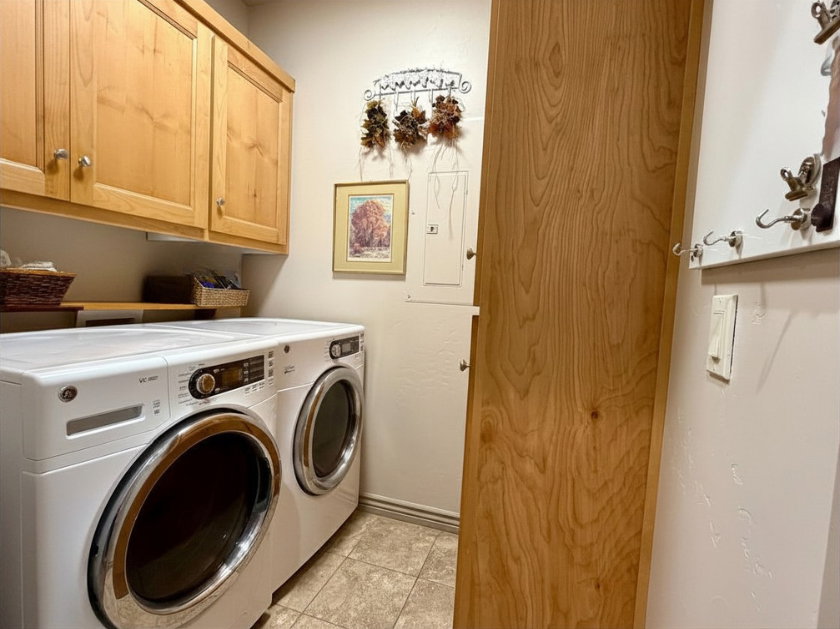 Laundry area featuring light wood-finish cabinetry, tile flooring, and a built-in wall-mounted coat rack