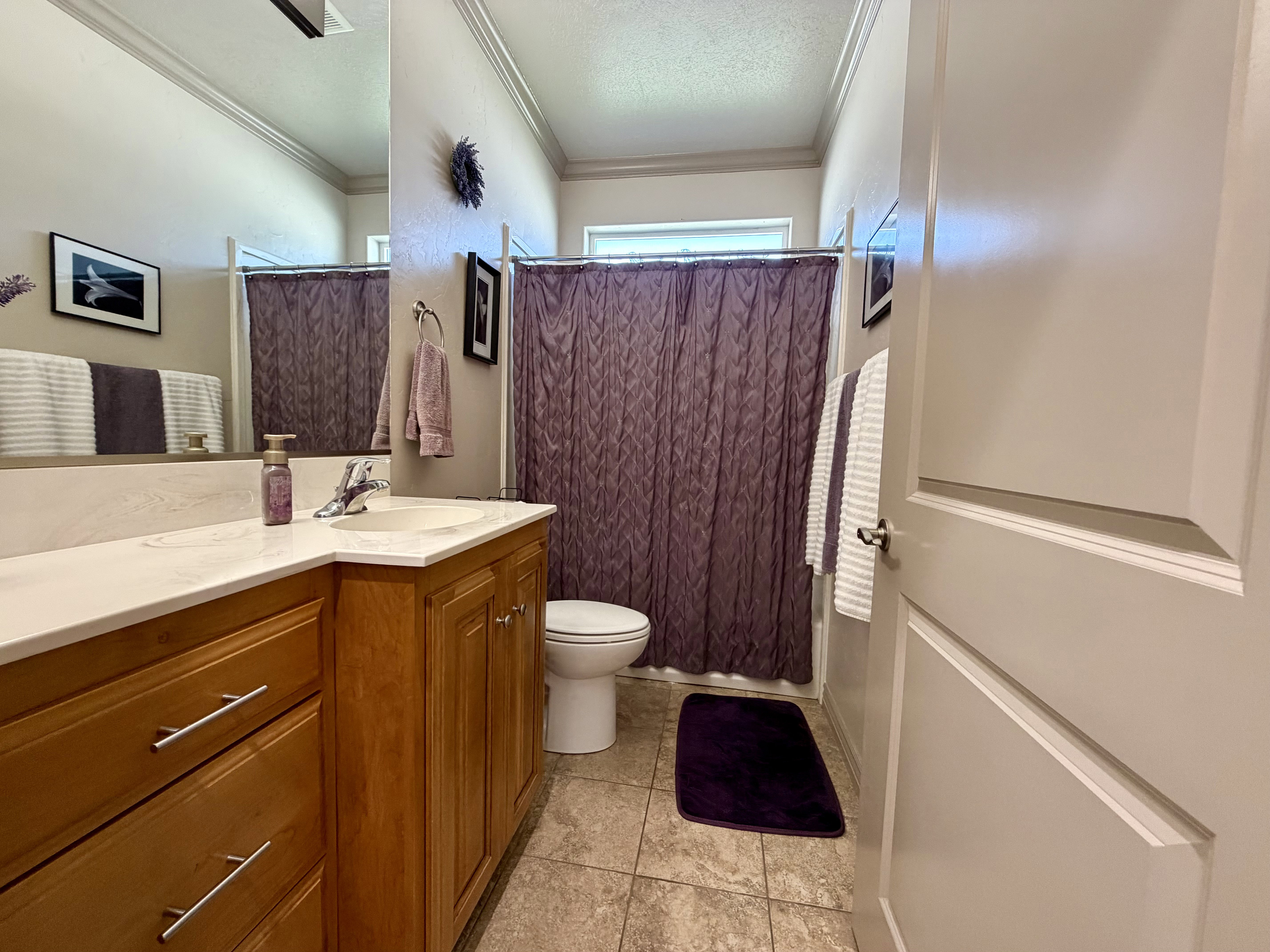 Bright and functional bathroom with shower/tub full mirror and tile flooring