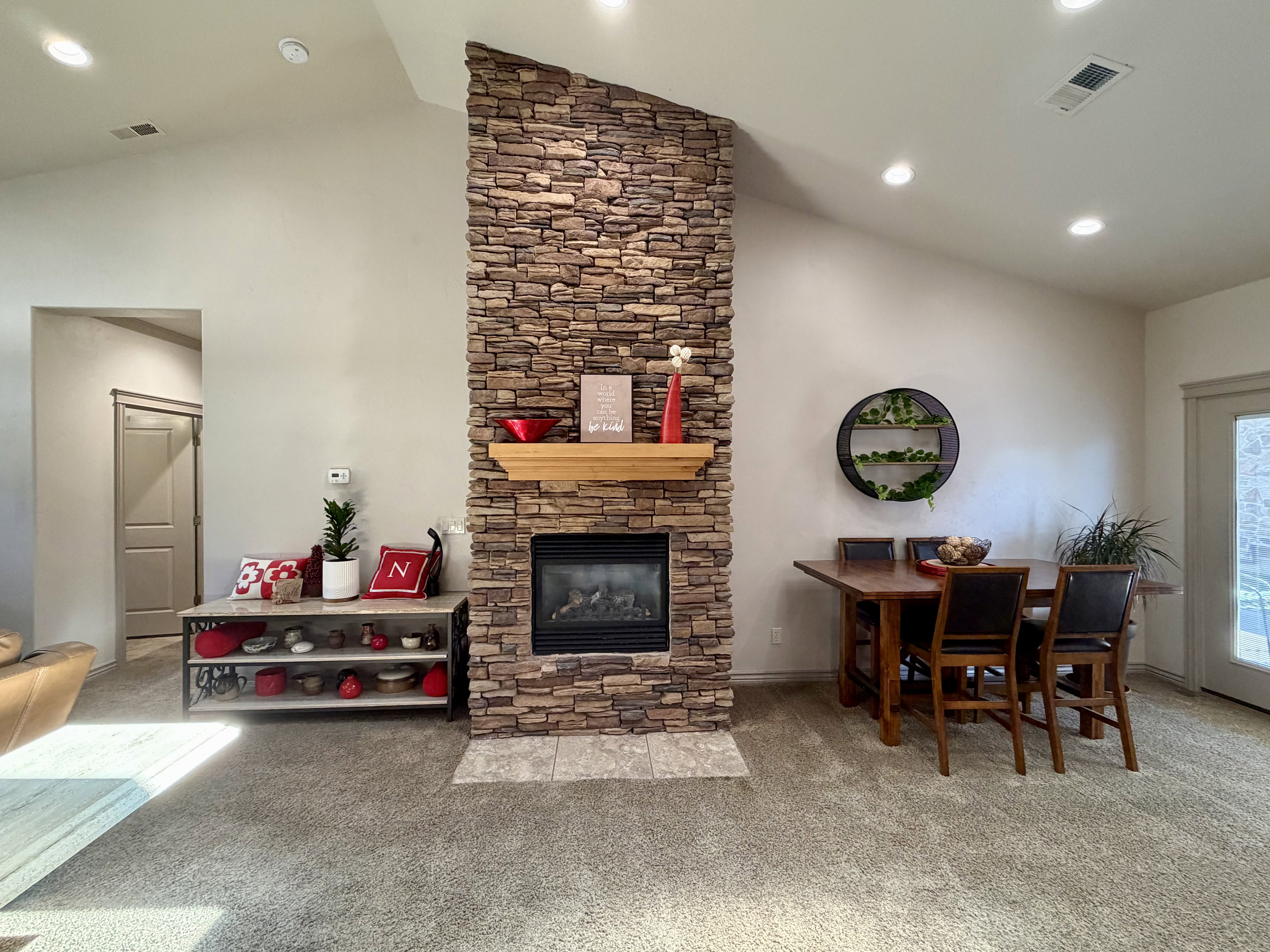 Stone-clad elegant fireplace with a wood mantel and gas insert creates a warm focal point