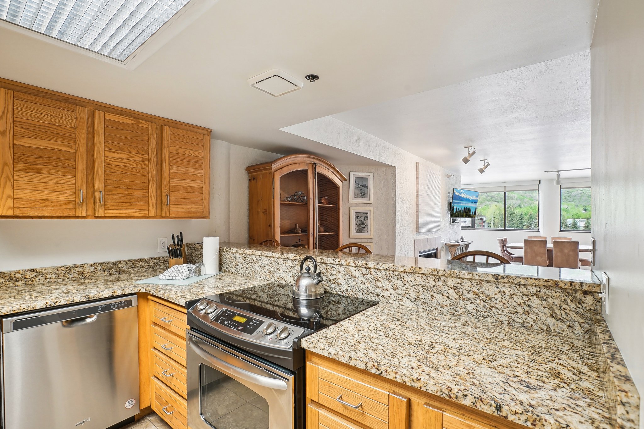 Kitchen featuring stone-finish countertops, wood cabinetry, and stainless steel appliances including a built-in dishwasher and range