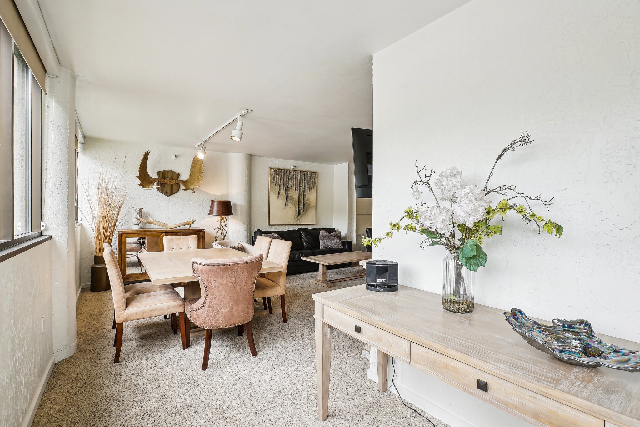 Open-concept living area featuring light-colored carpeting throughout