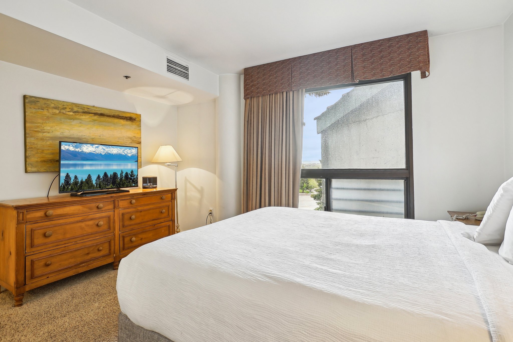 Bedroom featuring a large window, neutral carpeting, and a built-in air vent