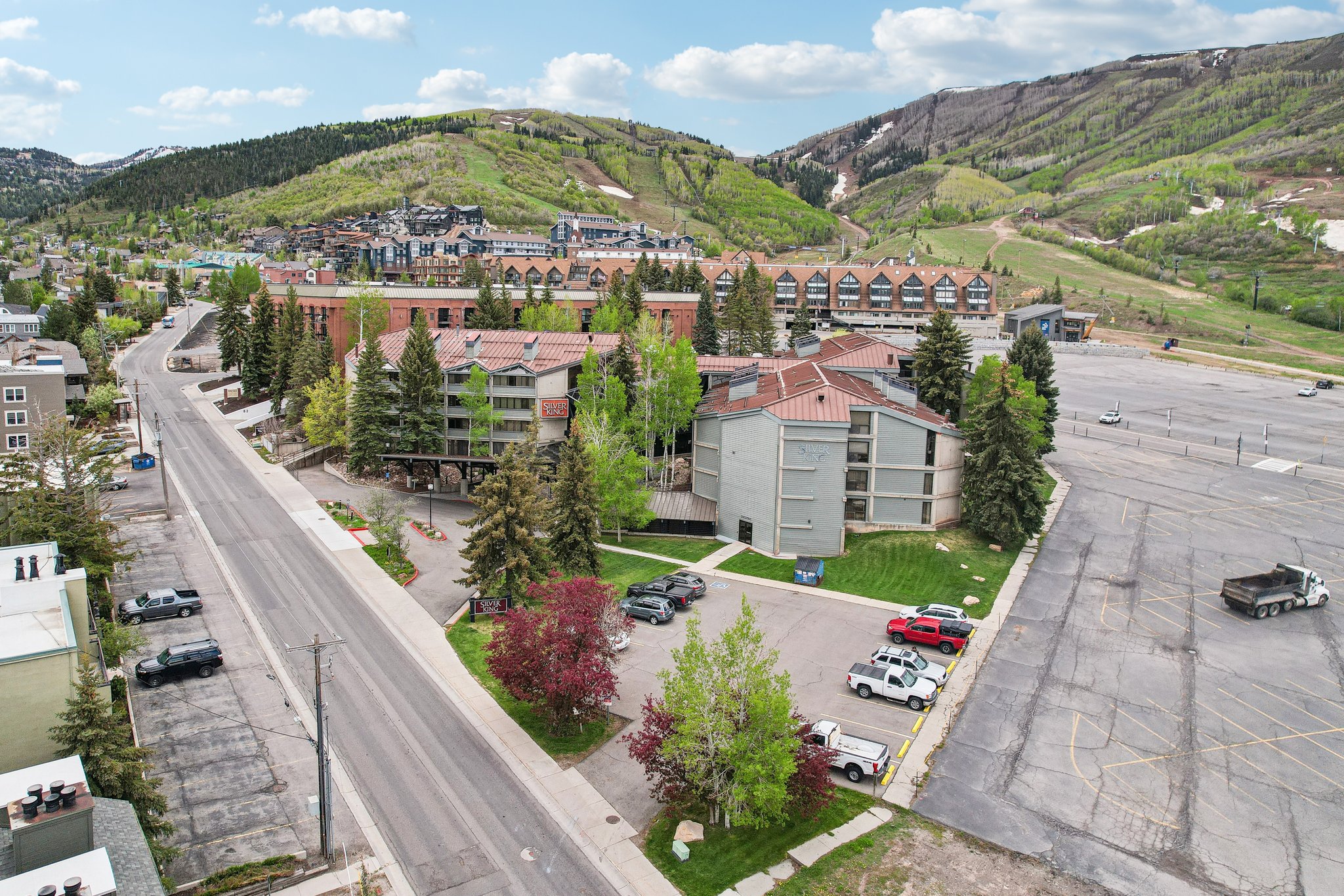 Multi-story residential buildings with pitched roofs surrounded by mature evergreen trees
