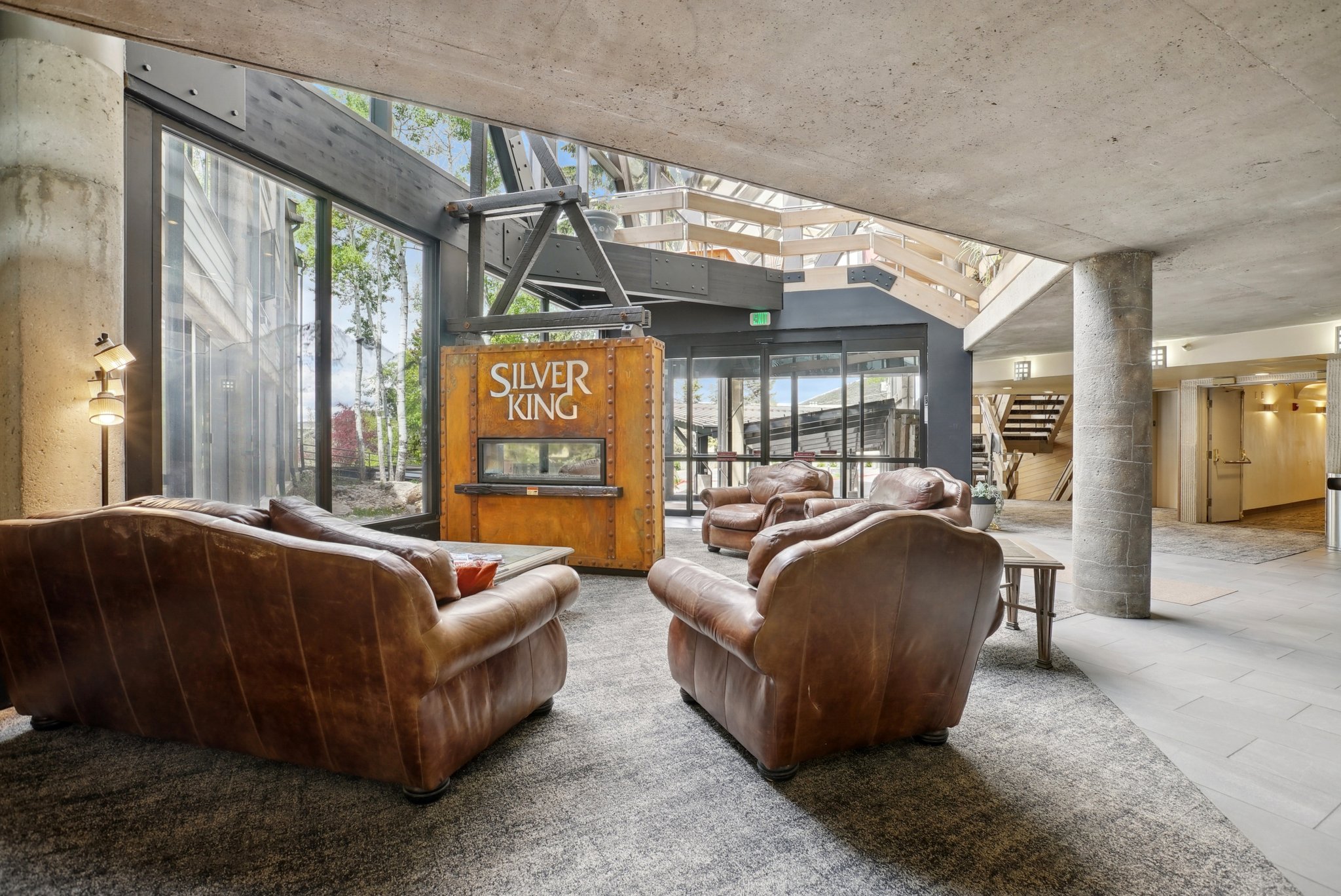 Spacious common area featuring an exposed concrete ceiling, large format window walls, and a distinctive "Silver King" kiosk