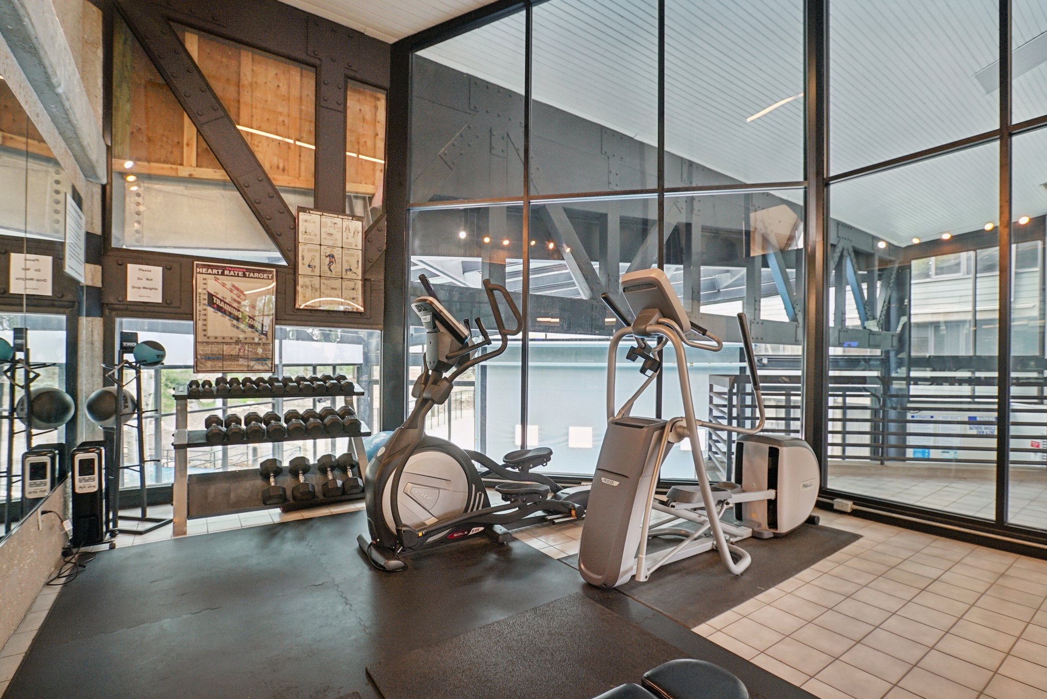 Fitness area featuring rubber flooring, mirrored wall, and floor-to-ceiling windows